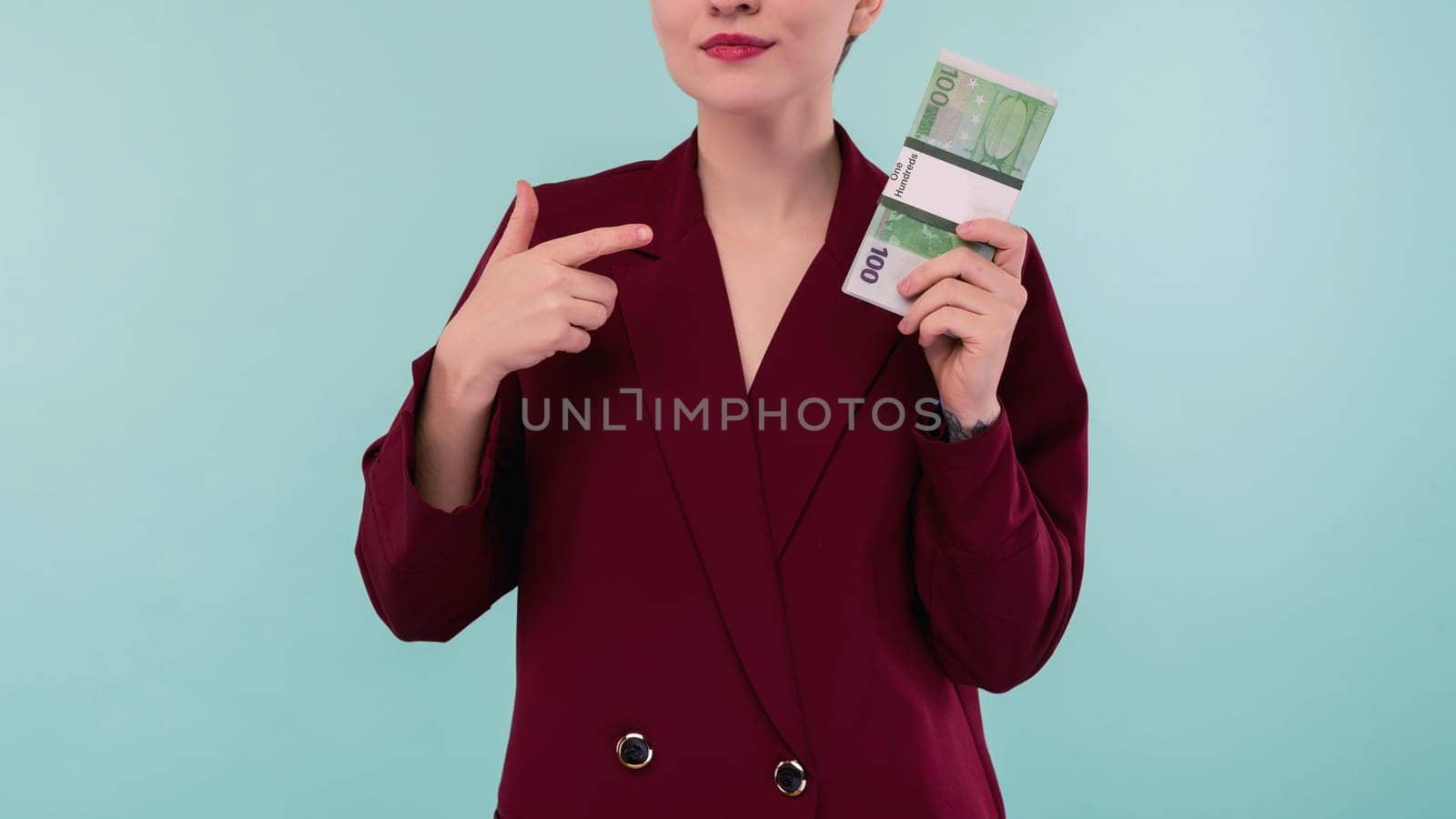 Portrait of beautiful young businesswoman pointing finger at money , on blue background - Image