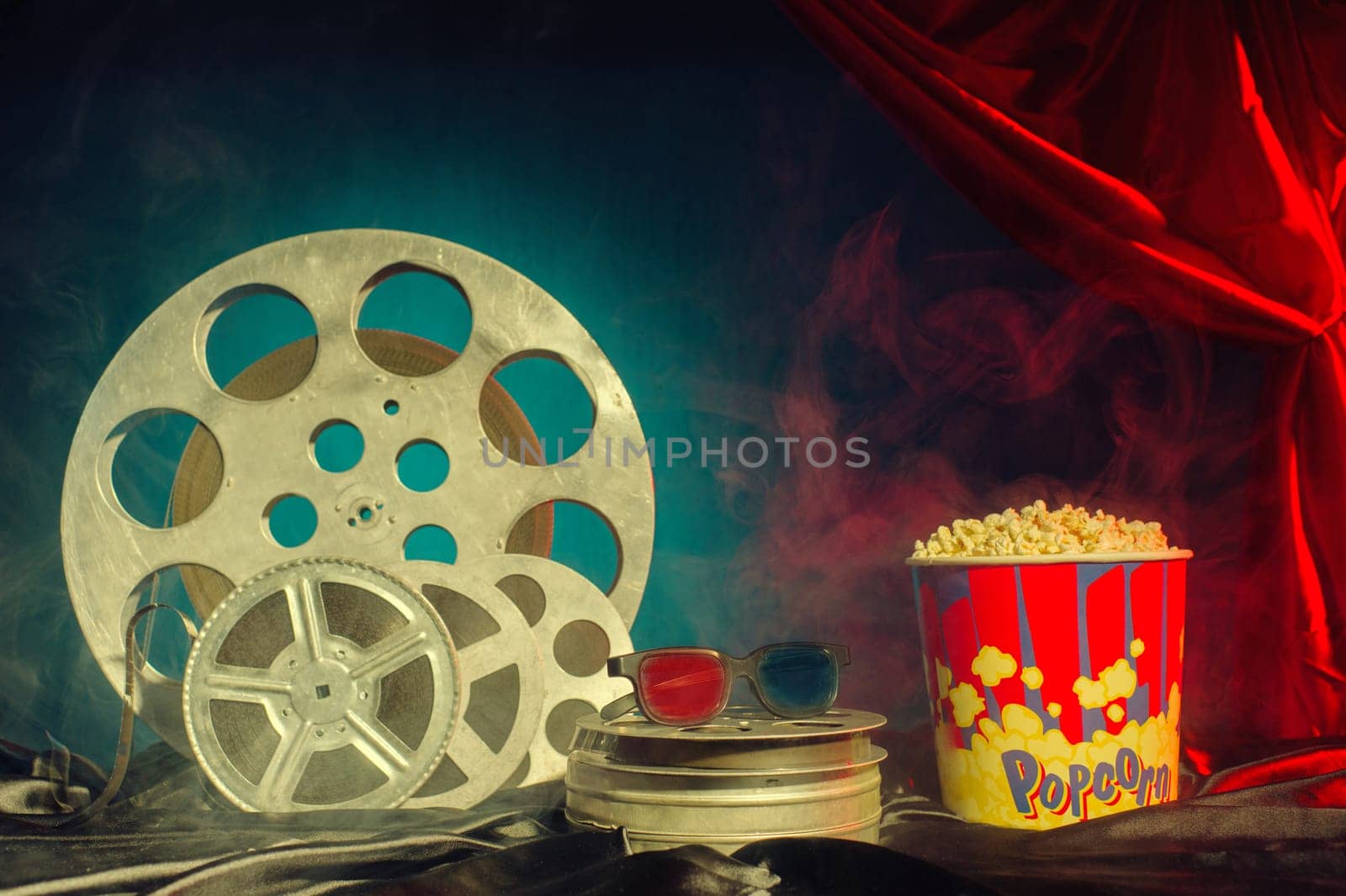 Old film reels, popcorn and 3d glasses on the table. Focus on glasses. Multicolored background. Evolution Film Media