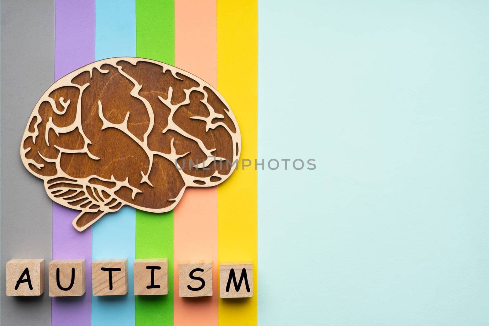 Mock up of the human brain on a colorful background. Six cubes with the inscription autism.