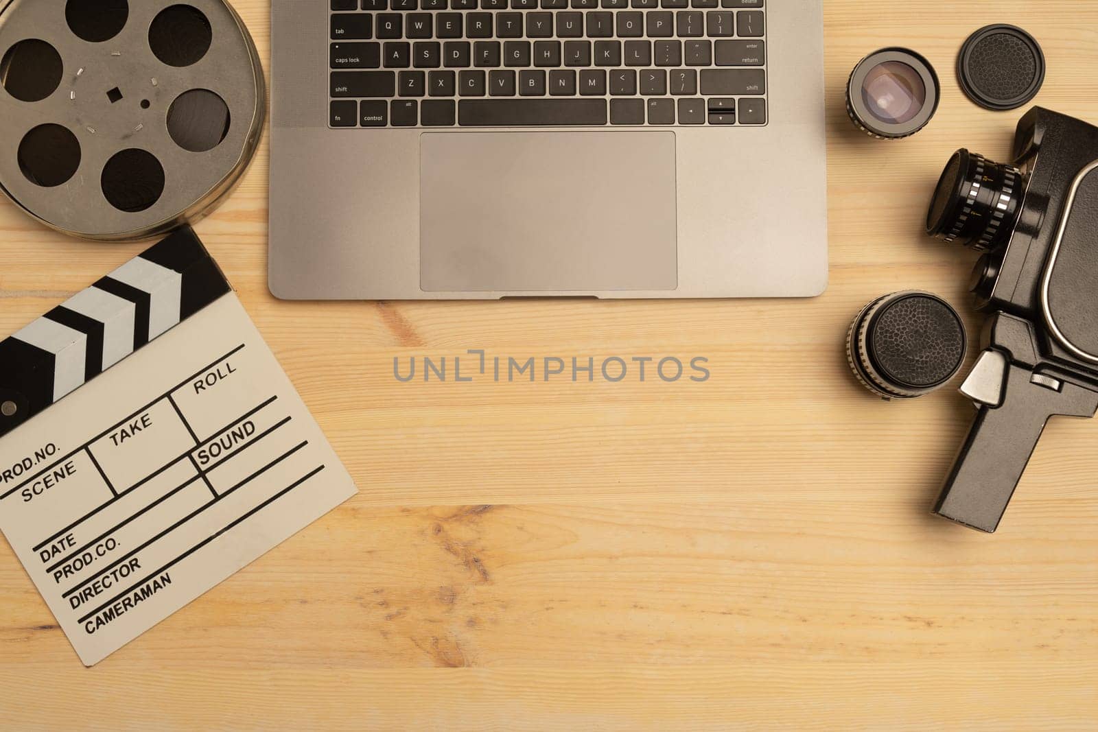 Movie clapper, laptop and camera on wooden background, top view