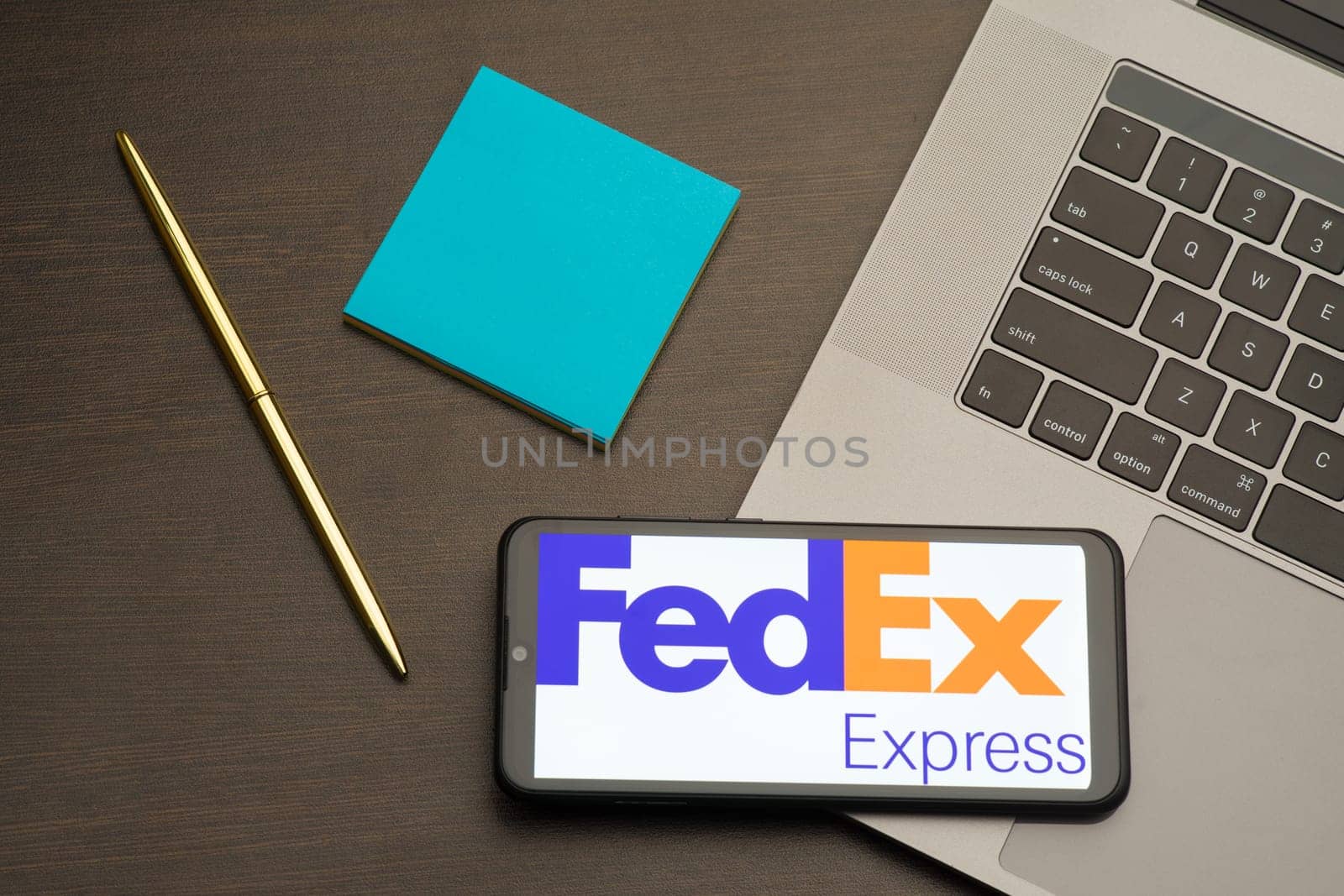 Tula, Russia - September 17, 2020: Logo FedEx on a smartphone near modern laptop on a table by zartarn