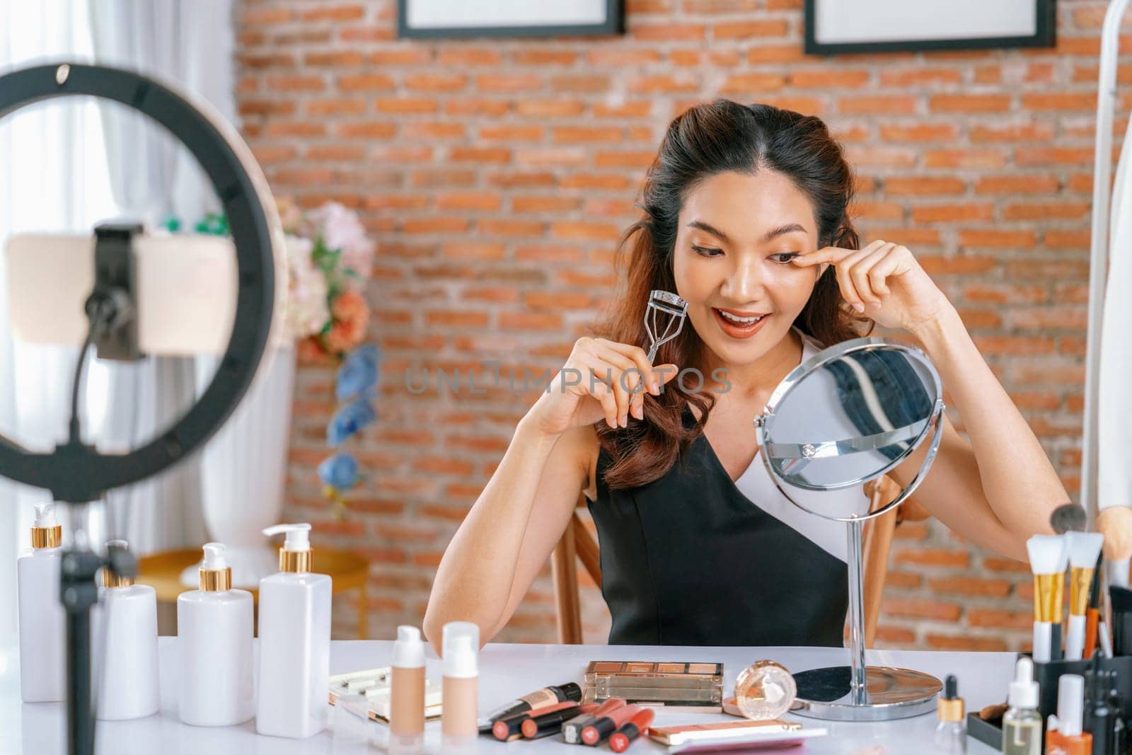 Asian Woman influencer shoot live streaming vlog video review makeup uttermost social media or blog. Happy young girl with cosmetics studio lighting for marketing recording session broadcasting online