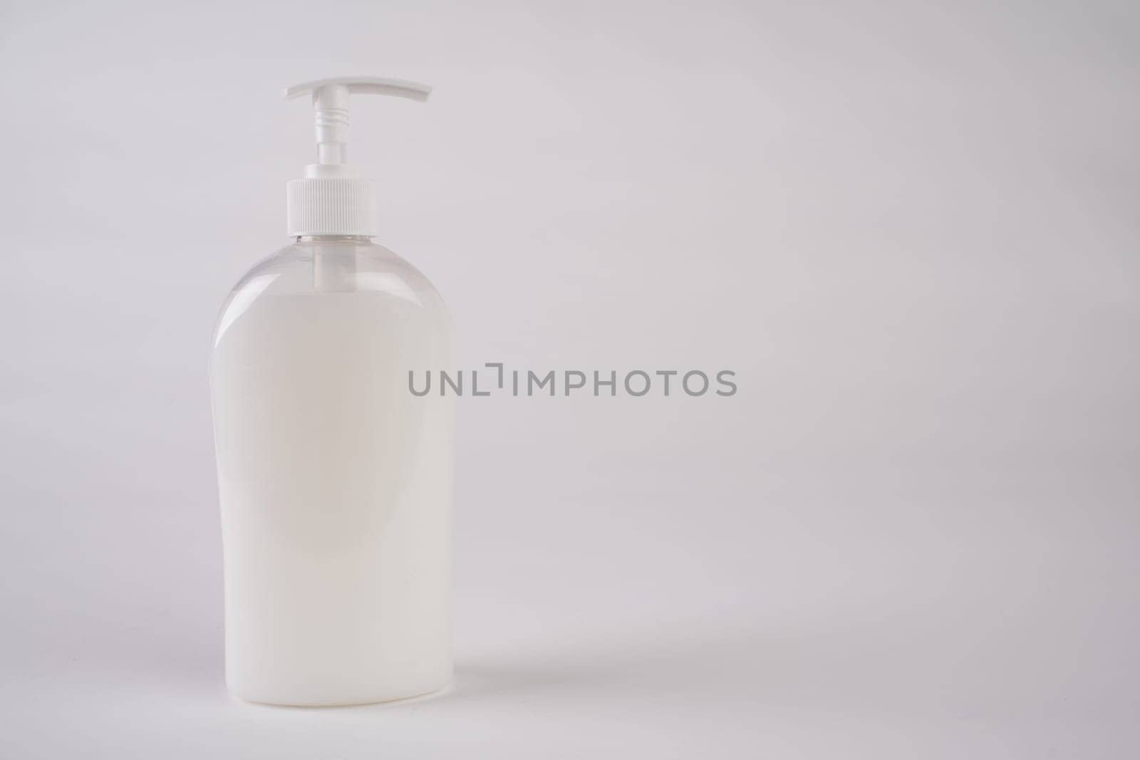 White unbranded dispenser bottle isolated on white background, cosmetic packaging mockup with copy space