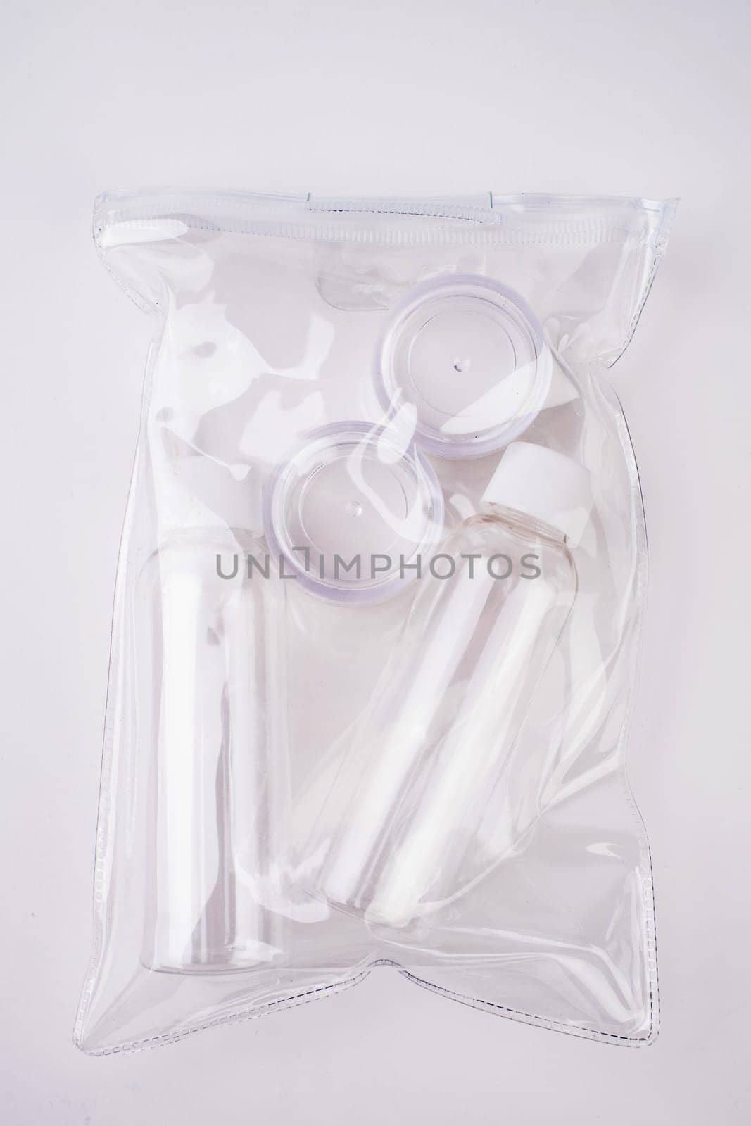 Plastic containers. Travel set on a white background. Plastic bottles for cream, shampoo in a sealed bag. Top view.