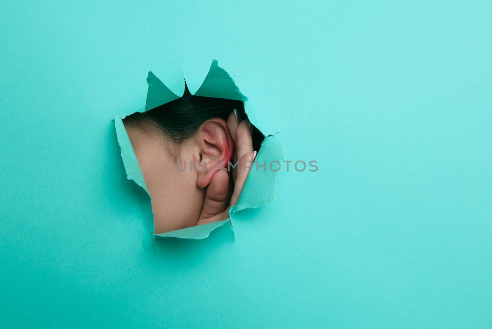 Female ear close-up. Copy space. Torn paper, blue background. by zartarn