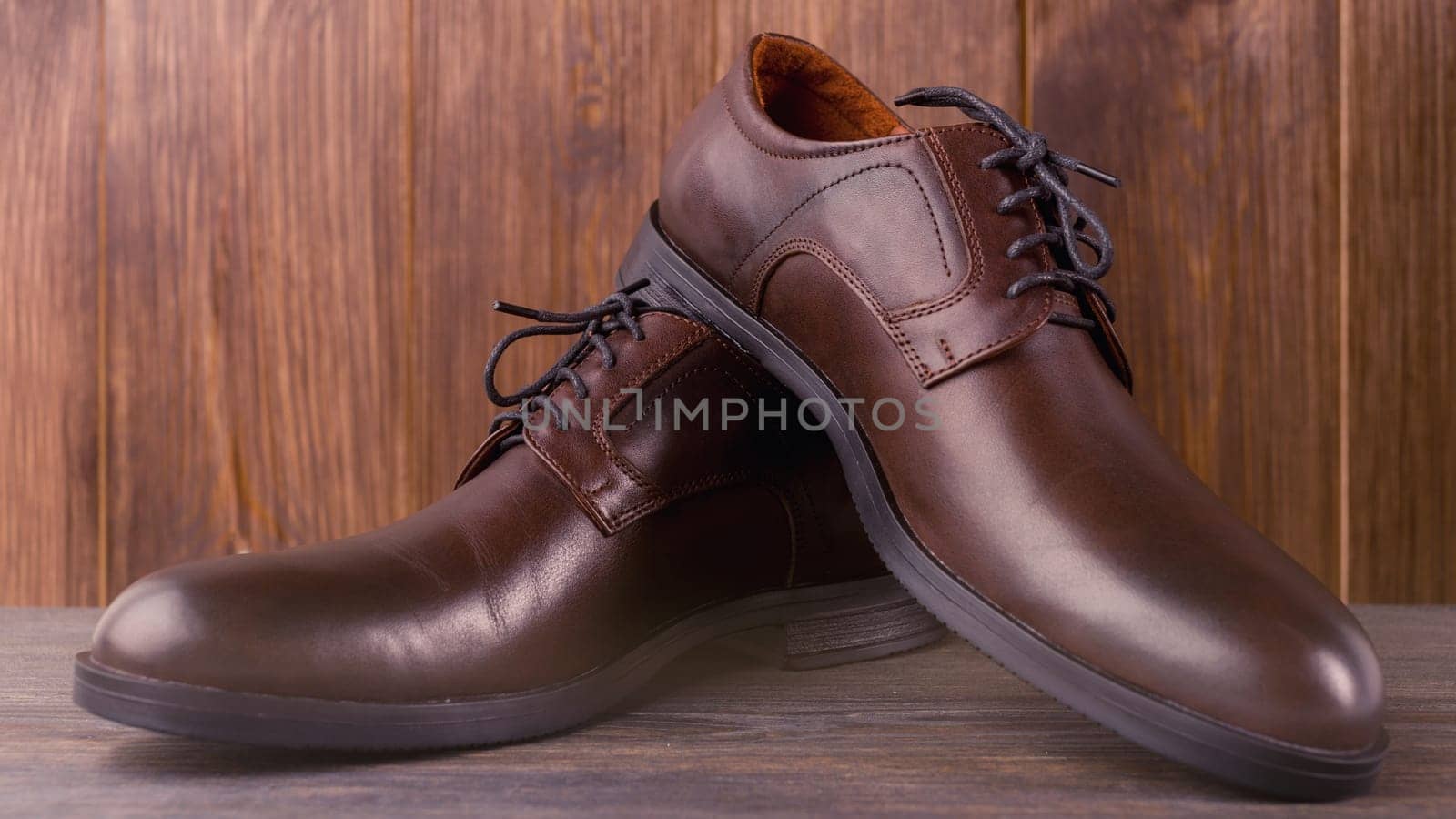 Fashionable men's classic brown shoes on a wooden background.
