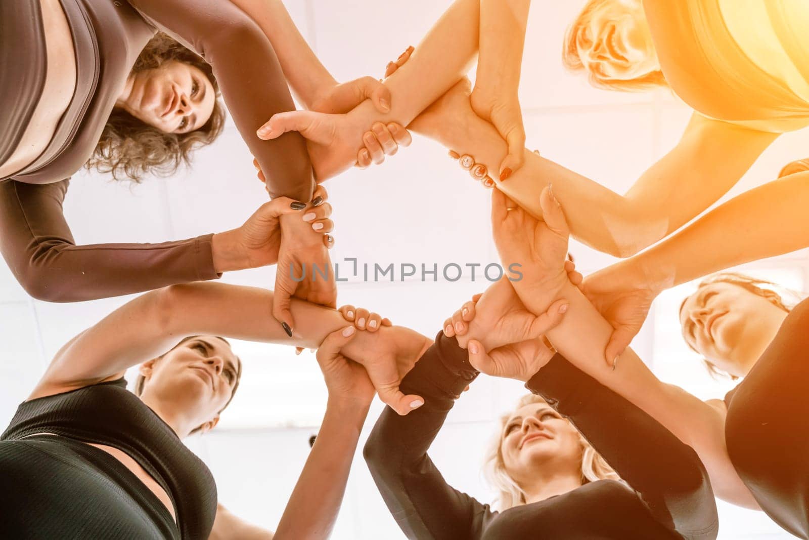Team of people holding hands. Group of happy young women holding hands. Bottom view, low angle shot of human hands. Friendship and unity concept by Matiunina