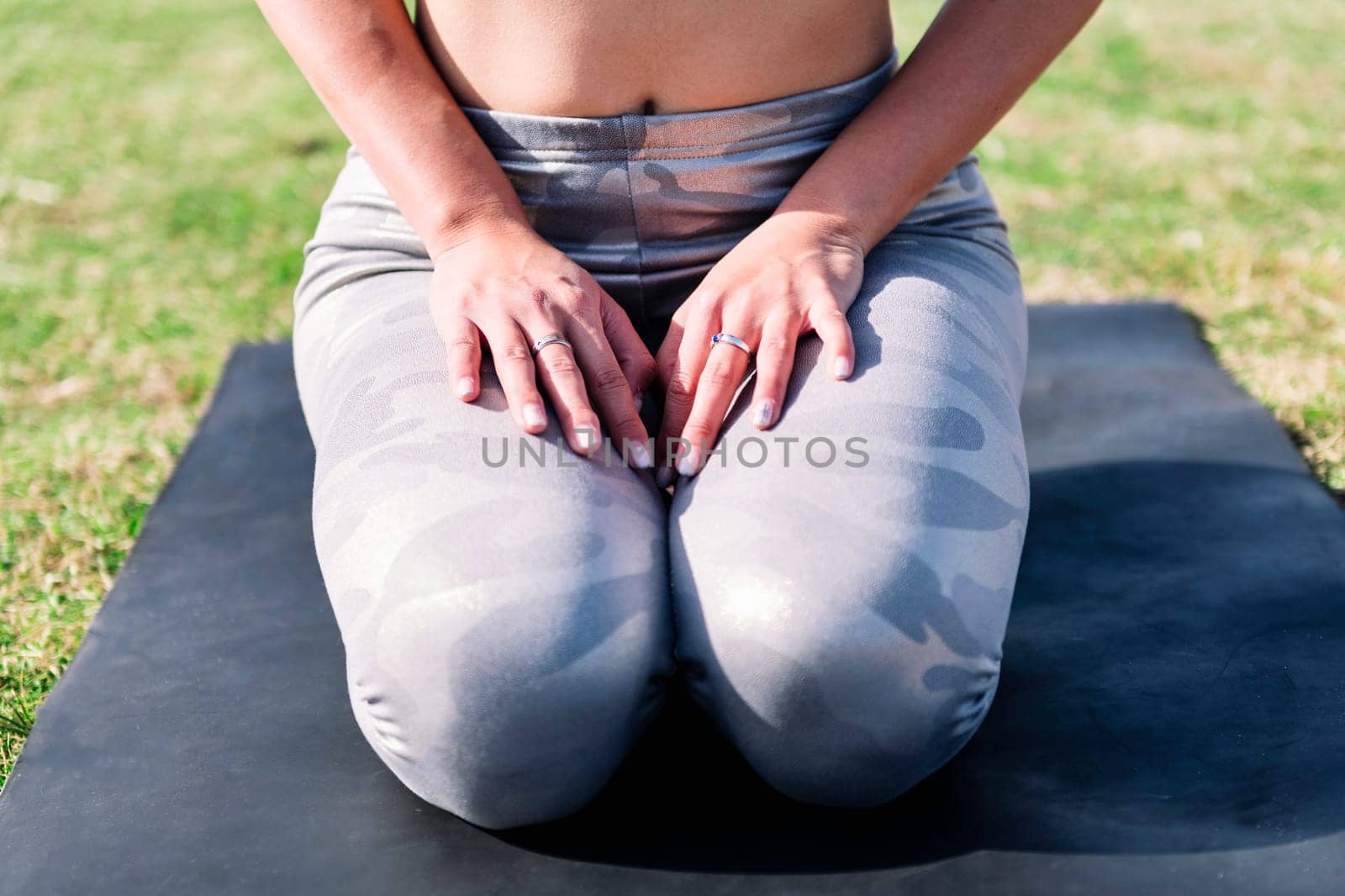 close up detail of legs and hands of an unrecognizable woman kneeling on a yoga mat doing relaxation exercises, active and healthy lifestyle concept