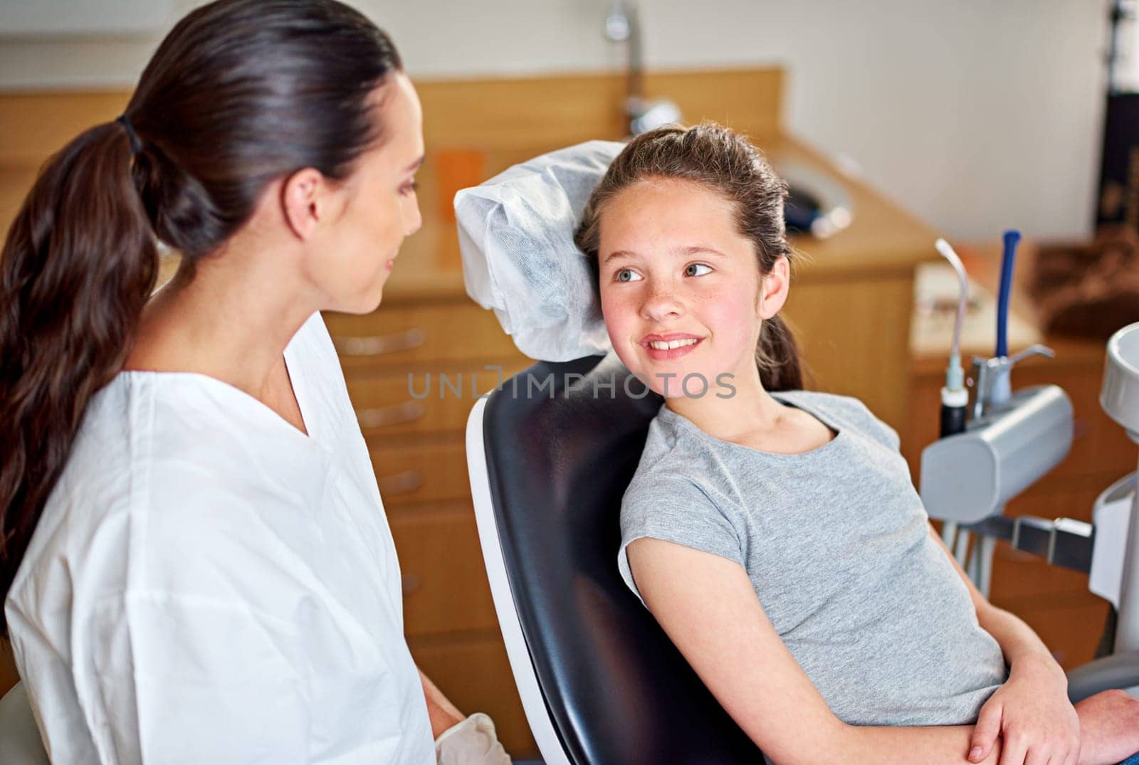 Dentist, child and oral hygiene consultation with conversation and talk for dental care. Clinic, smile and young girl with healthcare and wellness advice for mouth and teeth health at appointment.