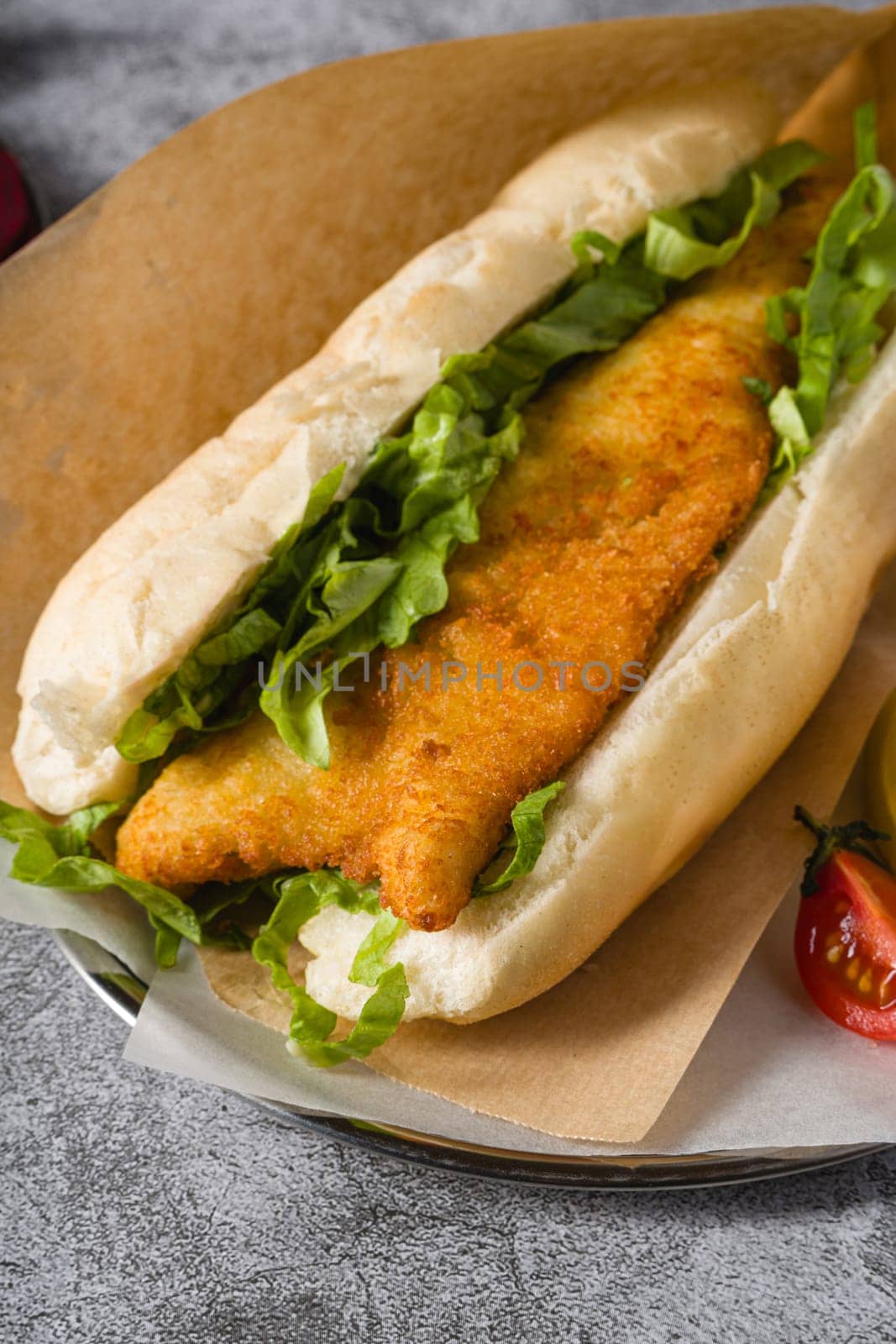 Fried fish sandwich with greens on the stone table. Turkish name Balik Ekmek