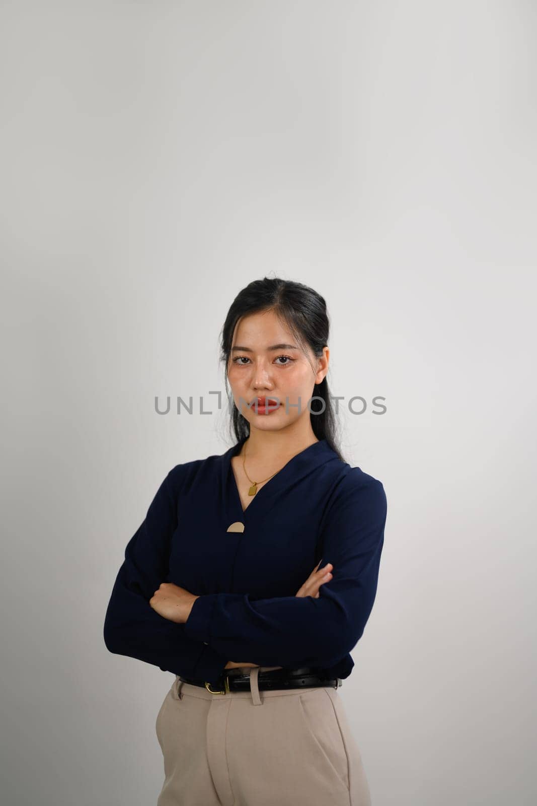 Attractive businesswoman standing with arms crossed and looking at camera confidently.