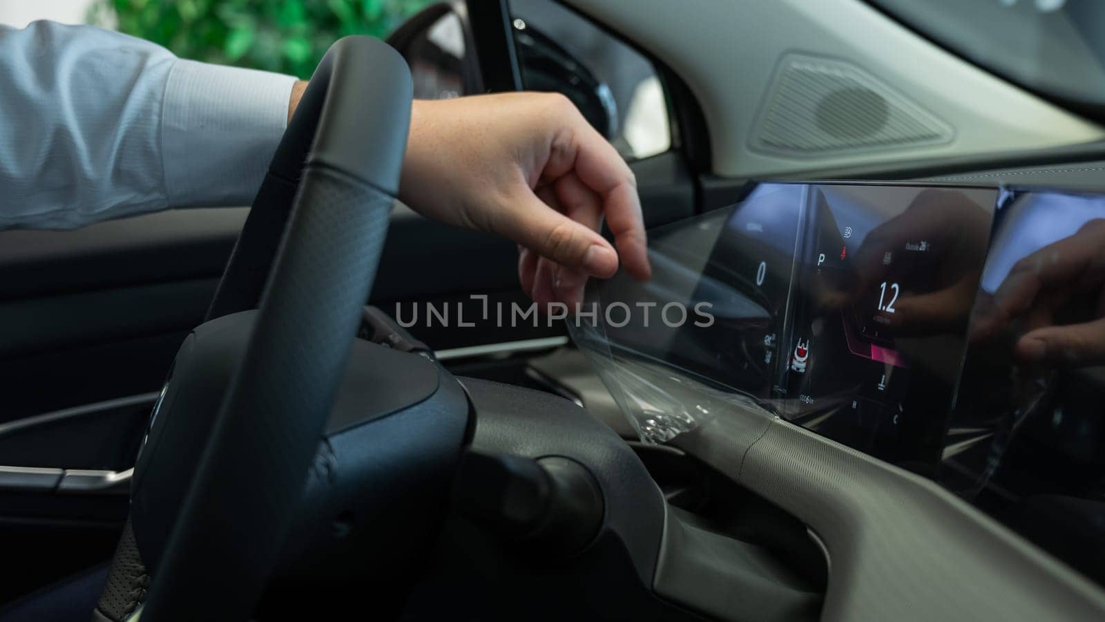 A man removes the protective film from the dashboard of a new car