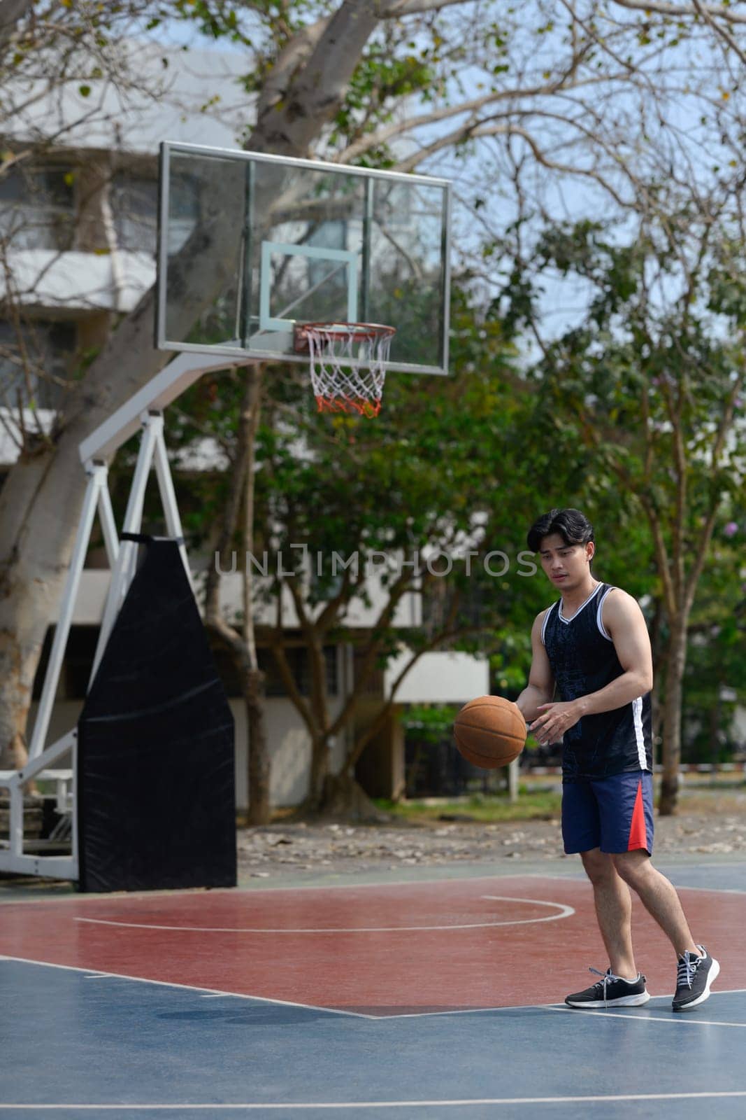 Young male athlete playing basketball on a public court. Sport, energy and healthy lifestyle concept.