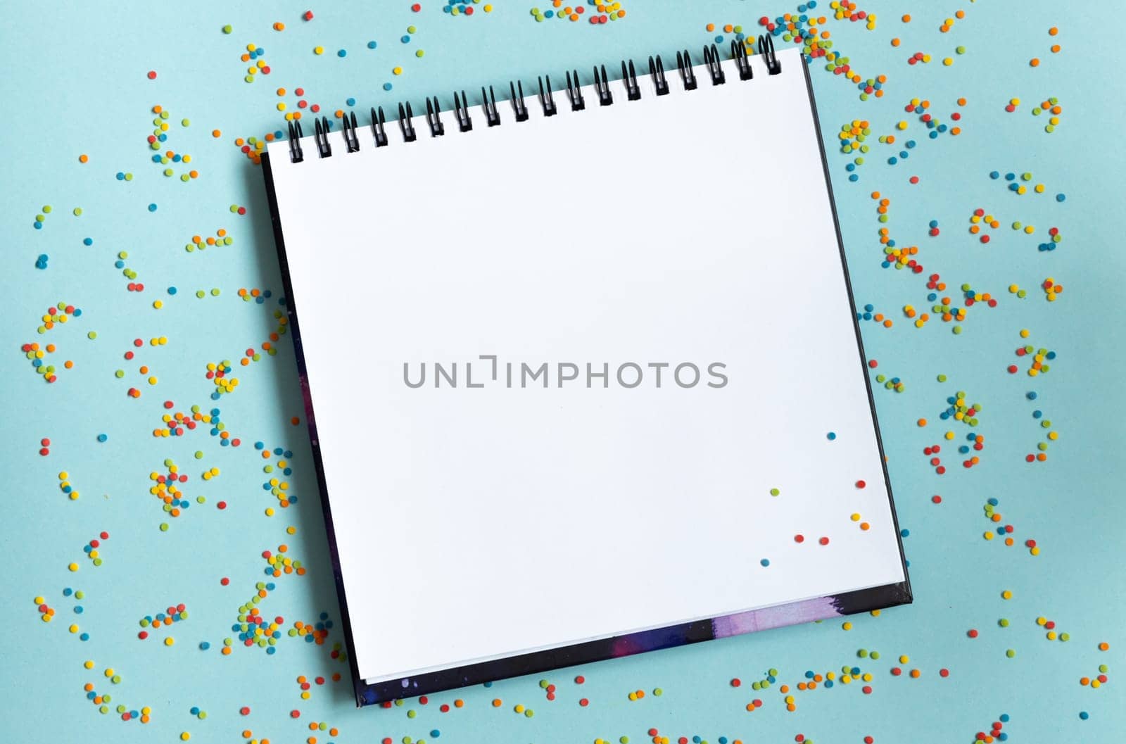 White open notebook on colorful background, festive, multicolored paper confetti. by Ri6ka