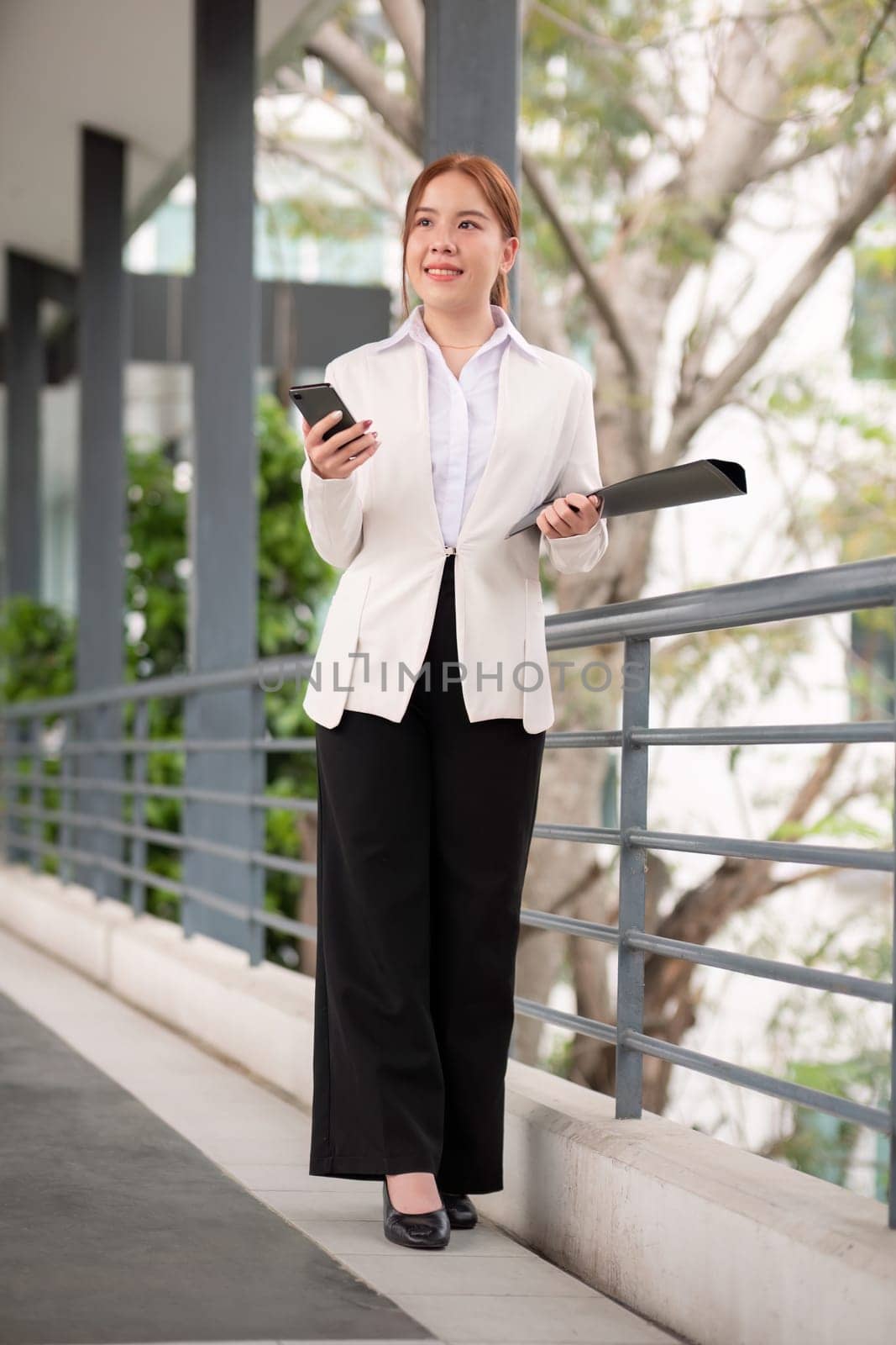 Asian business woman beautiful with smart phone and document file, asian woman with smartphone walking go to work. Preparation for the working day by nateemee