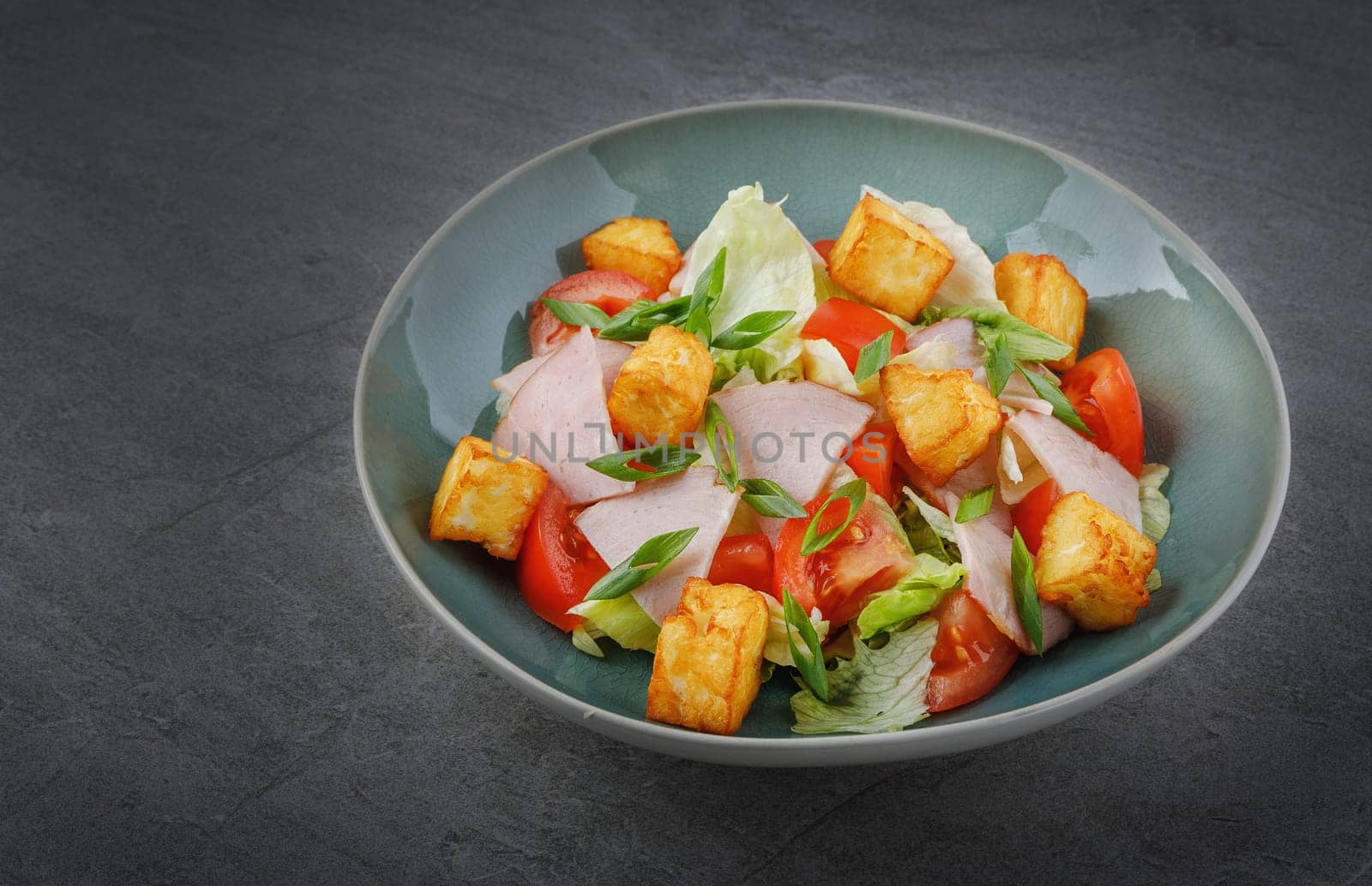 appetizing salad with ham and halloumi cheese on a stone background for the site