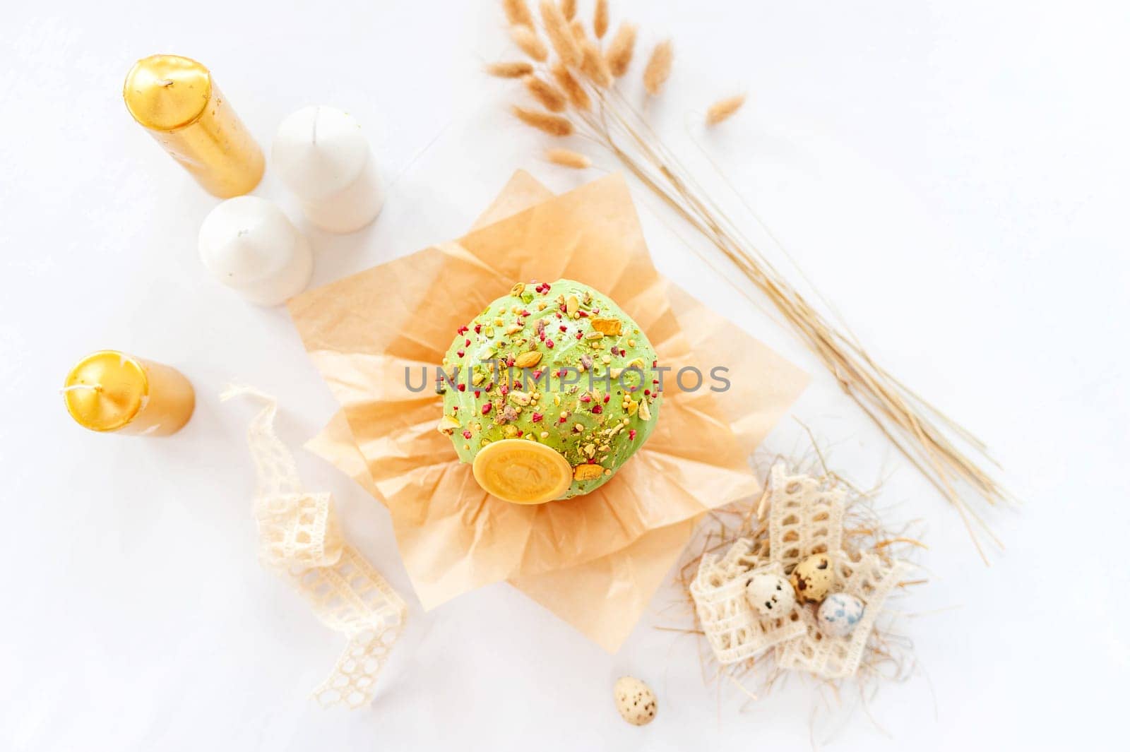 Traditional easter cake or sweet bread, quail eggs and green meringues in shape of nest over white background. Top view, close up. Easter treat, holiday symbol.