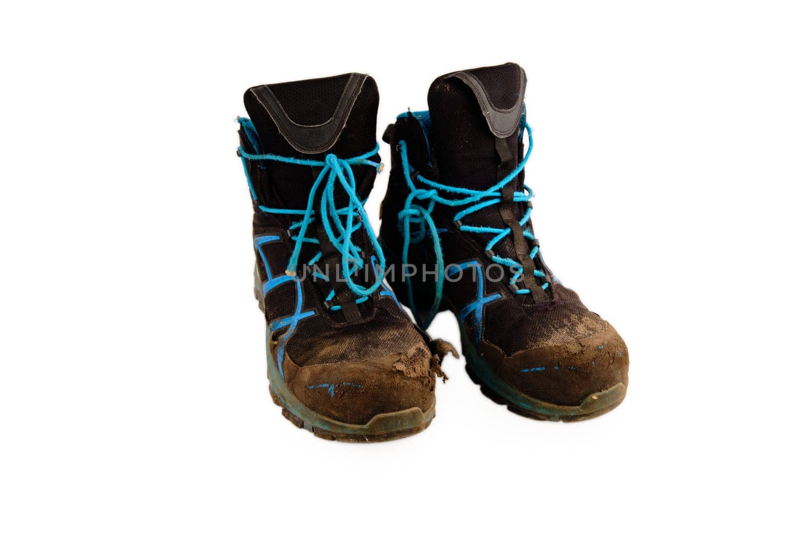 A pair of old hiking boots dirty and battered after a long hike on a white background