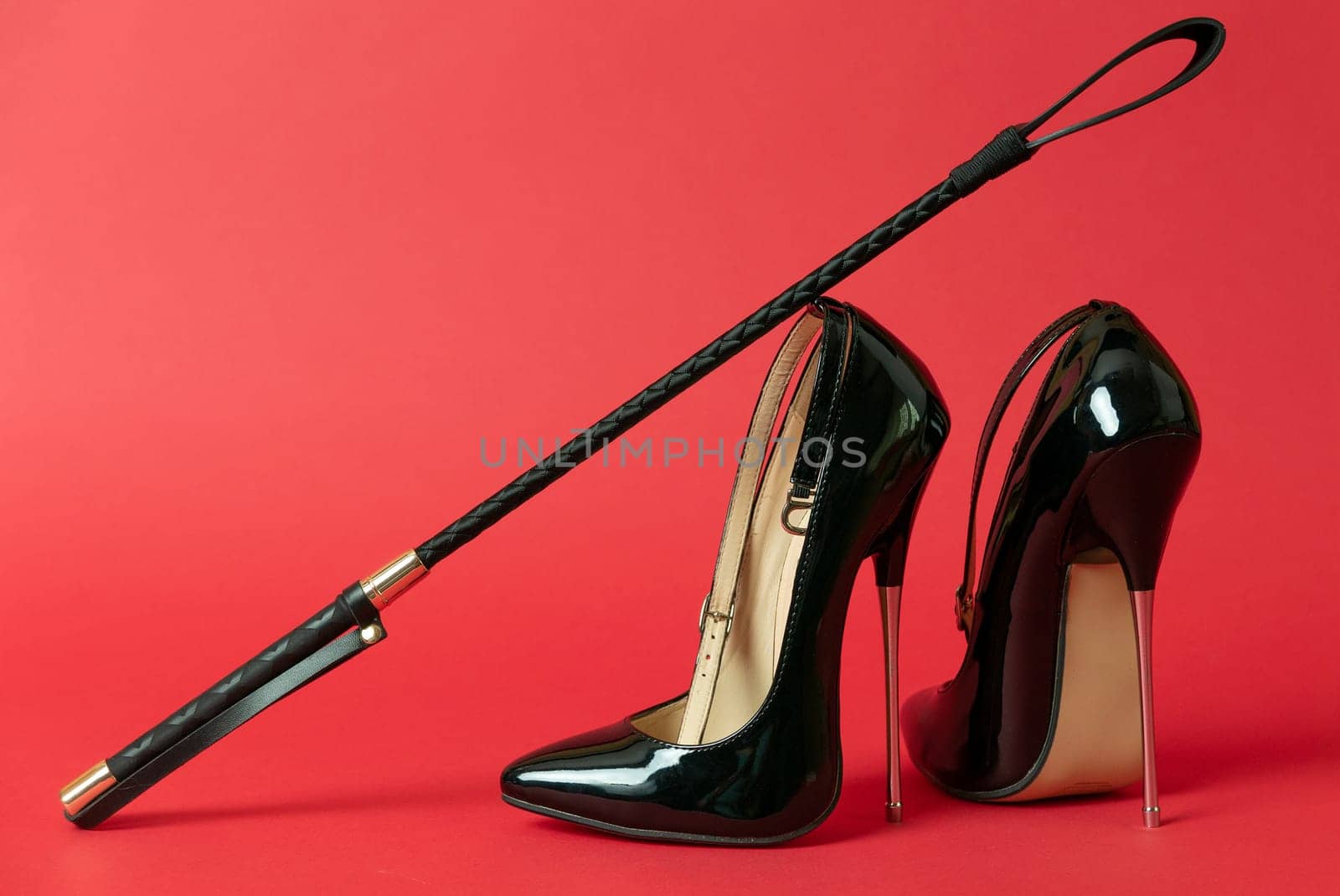 Black shiny high heel shoes and a whip on a red background by zartarn