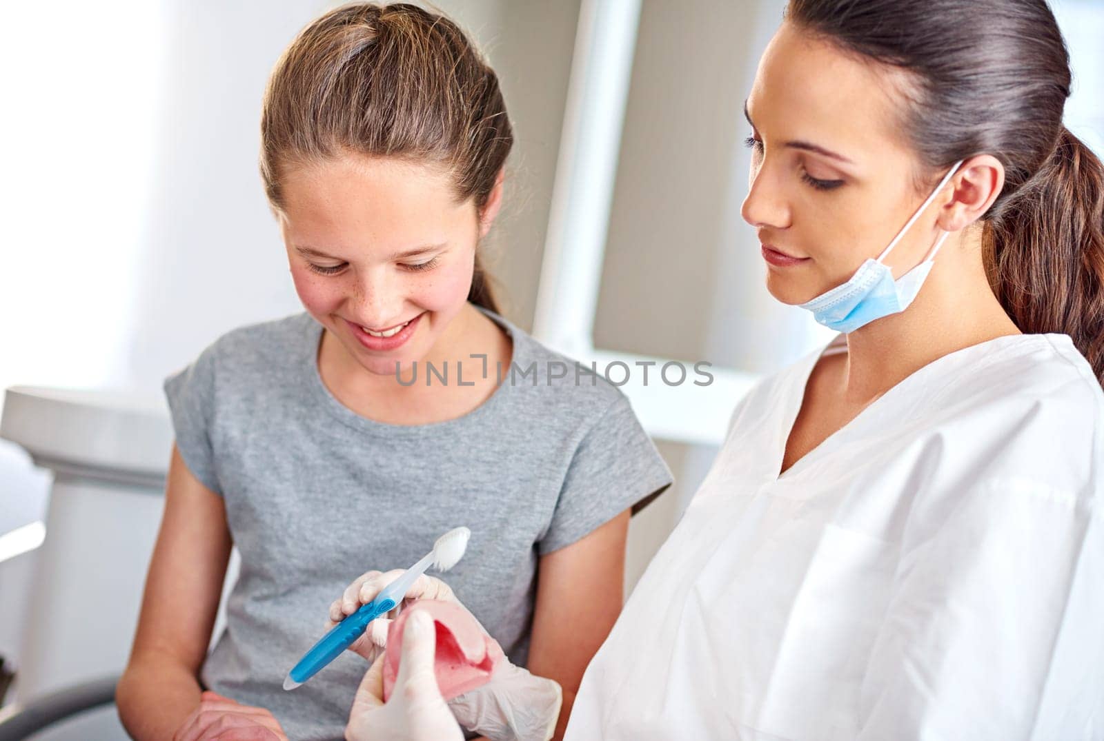 Dentist, child and oral hygiene with dentures for teaching on dental care, cleaning and consultation. Advice, girl and orthodontist holding toothbrush for gum disease, treatment and healthy teeth.