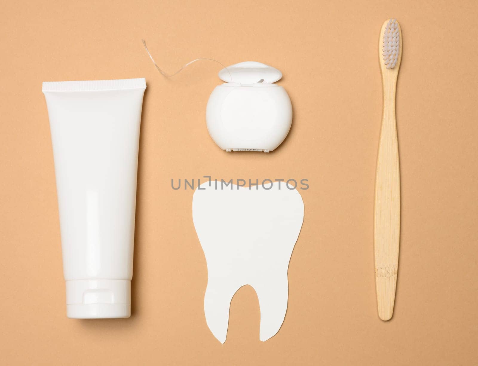Toothbrush, toothpaste and paper tooth on a brown background, oral hygiene. View from above
