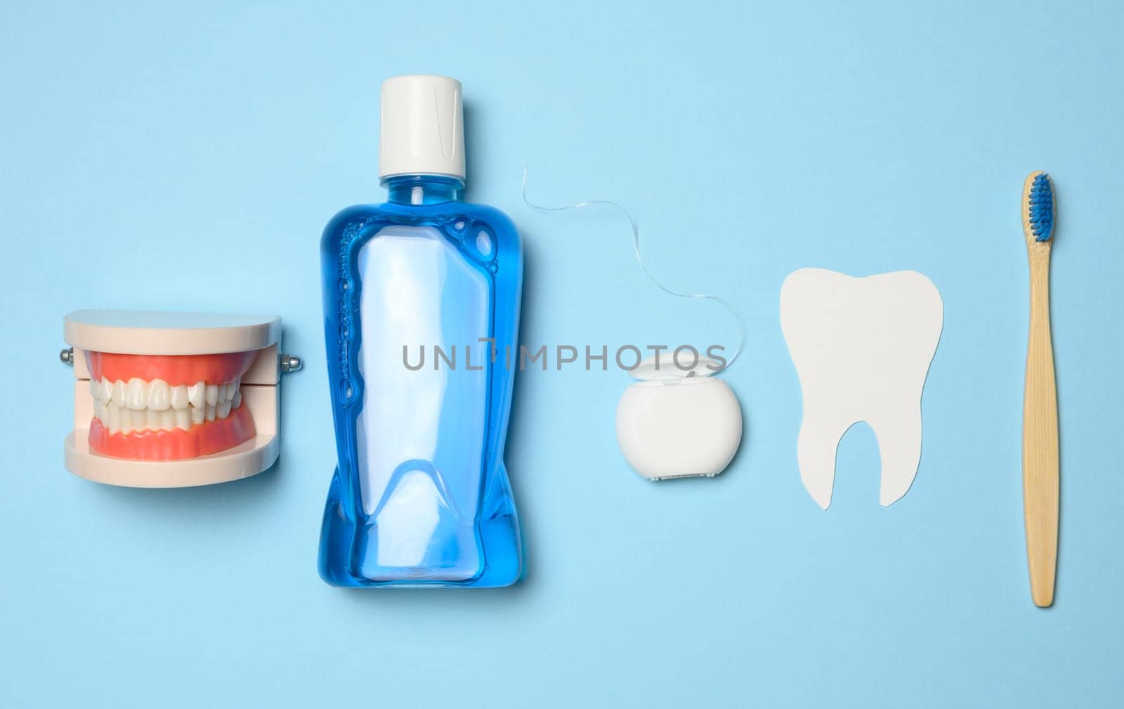 Plastic bottle with mouthwash, wooden toothbrush on blue background by ndanko