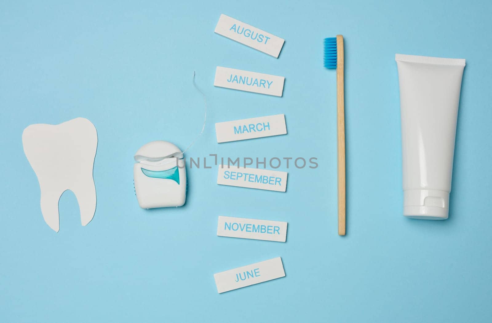 Tube with toothpaste, dental floss and toothbrush on a blue background, oral hygiene. by ndanko