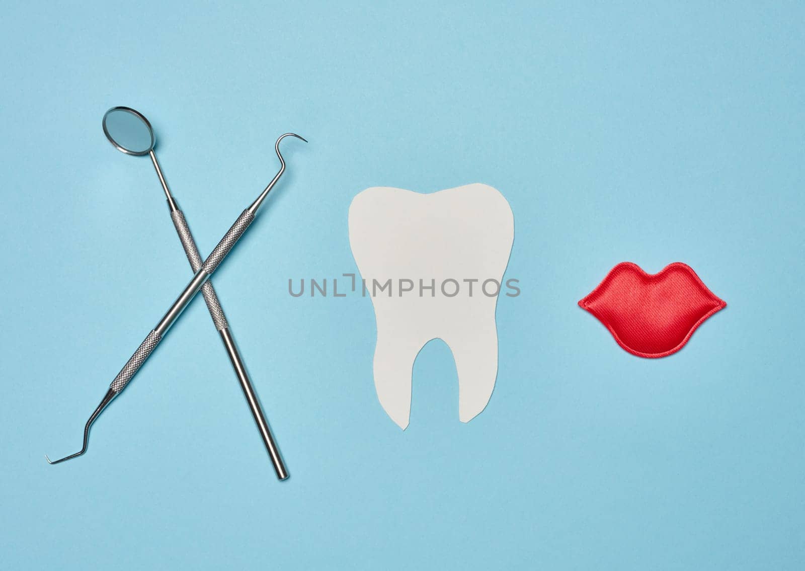 Paper human tooth and dentist medical instruments on blue background by ndanko