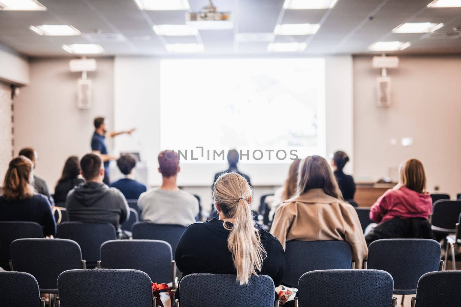 Speaker giving a talk in conference hall at business event. Rear view of unrecognizable people in audience at the conference hall. Business and entrepreneurship concept