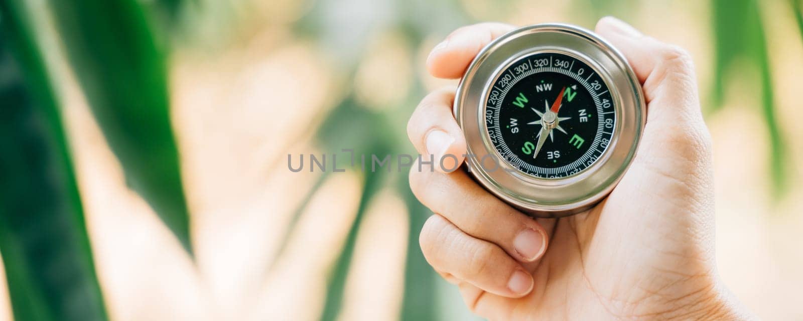 A traveler holding a compass in a park searches for guidance and direction amidst nature beauty. The compass in the woman hand signifies exploration and a journey to find her path.