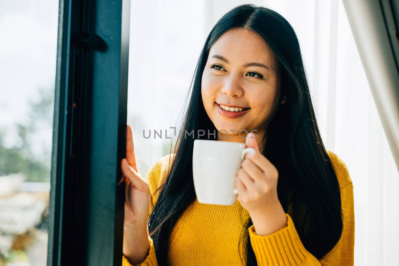 Embracing morning joy, Woman with a cup of tea stands by the window smiling at the sunrise in her home. Reflecting relaxation happiness and a sense of contemplation.