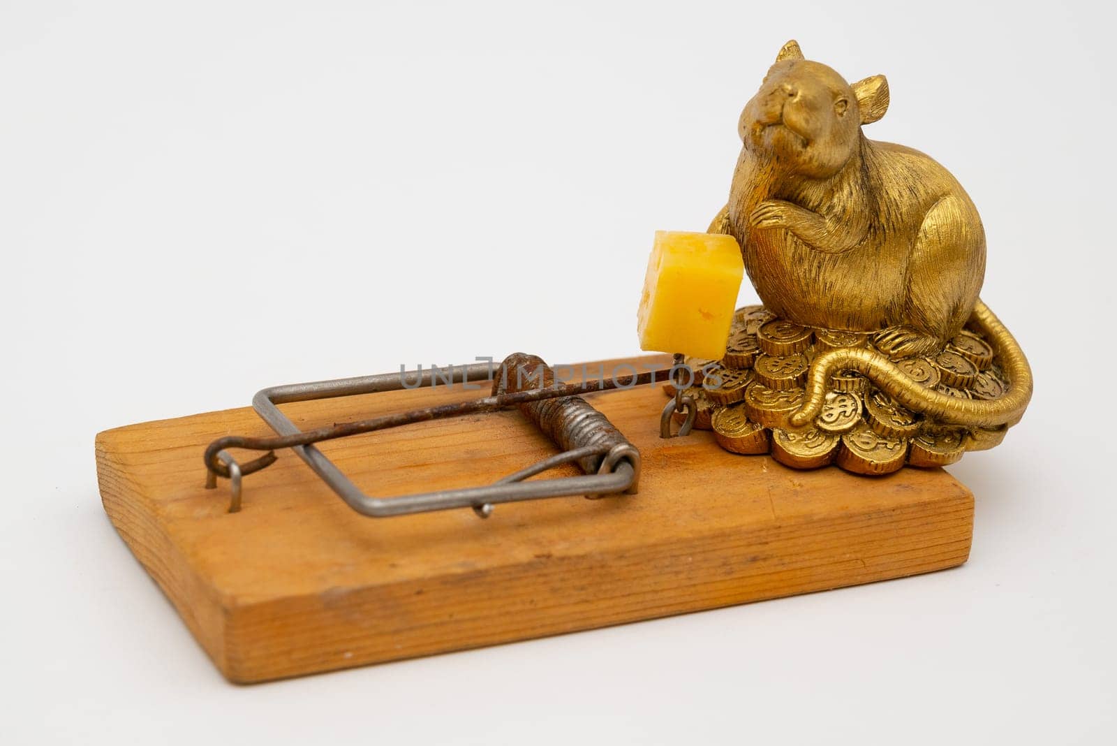 figurine of a rat near cheese in an old mousetrap