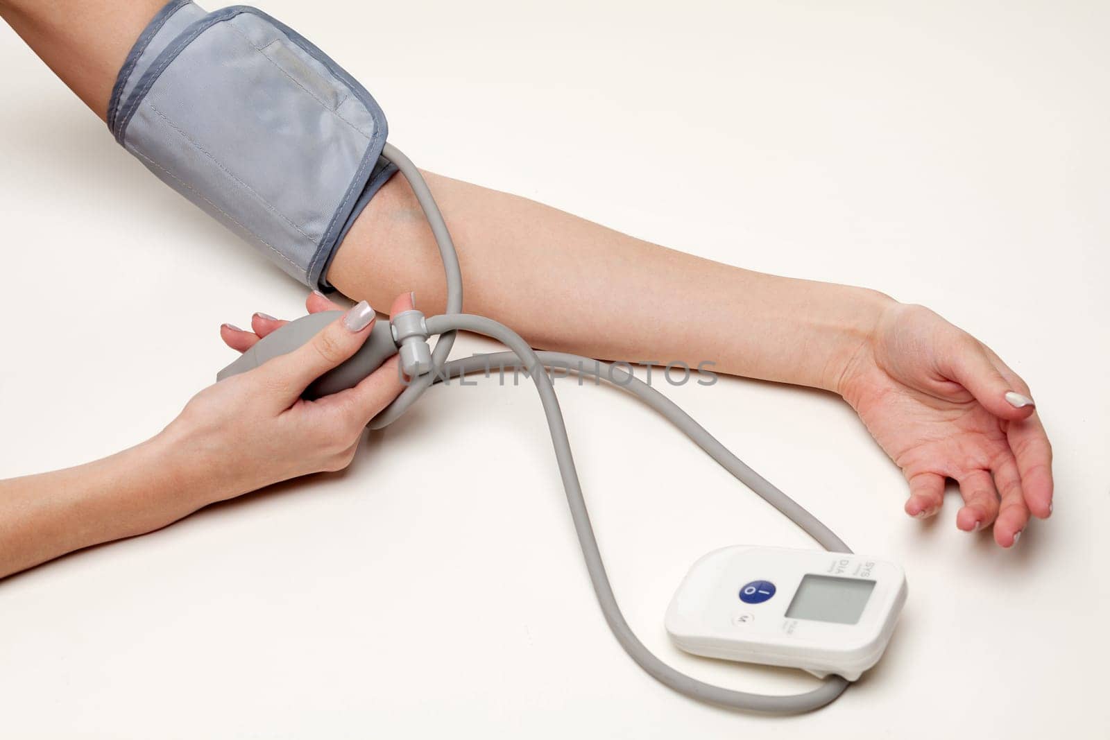 Blood pressure measurement. Woman hands with tonometer on white background. by Nobilior
