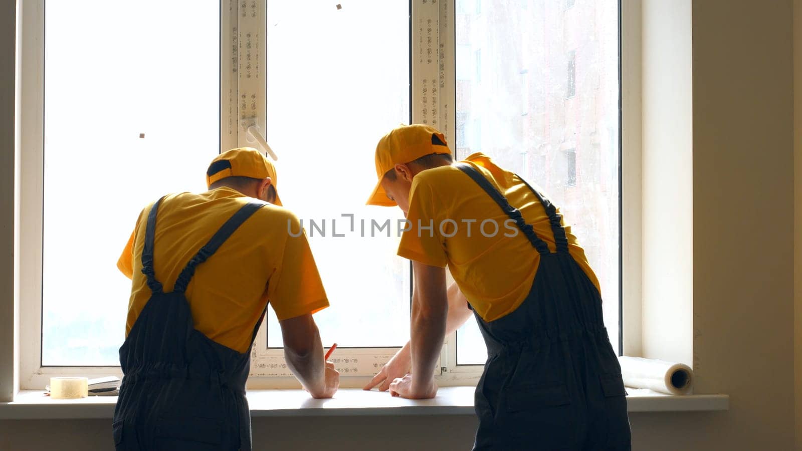 Workers studying the draft of a house. Builders are prepare plan of a large apartment.