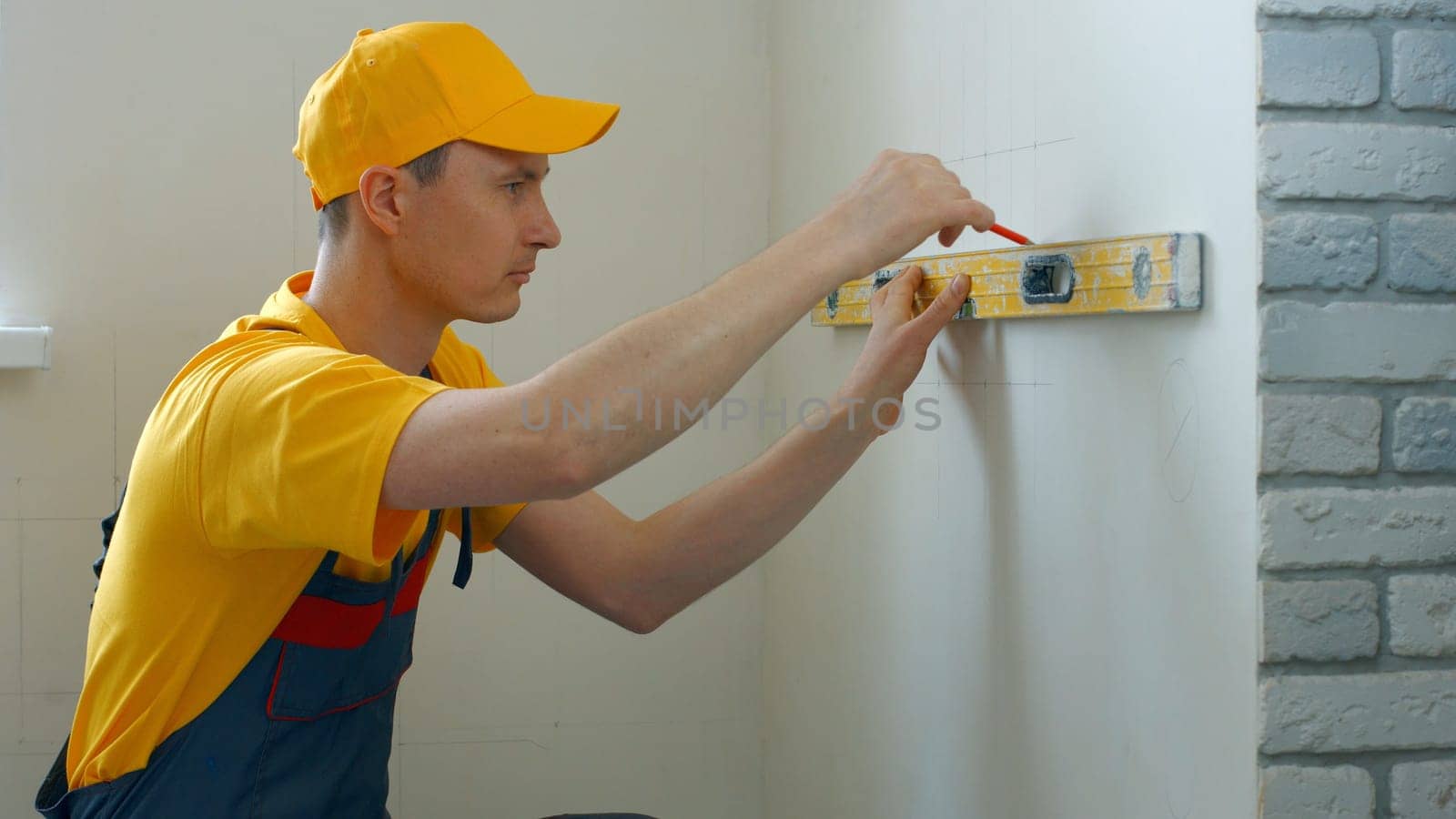 Worker draws markings on the wall. Lines are drawn for fastening.