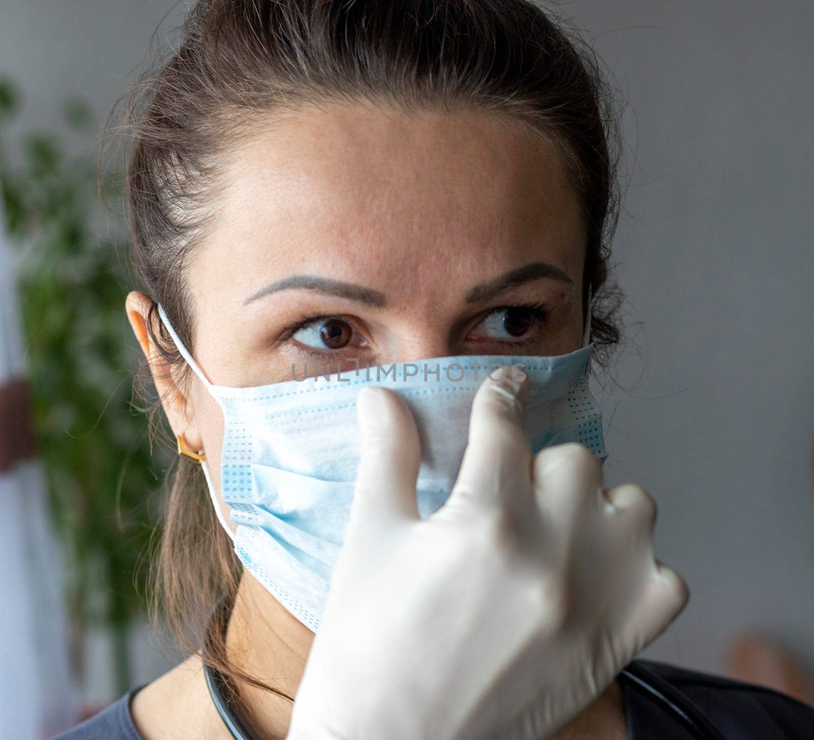 Shot of the nurse in the medical gloves holding medical mask