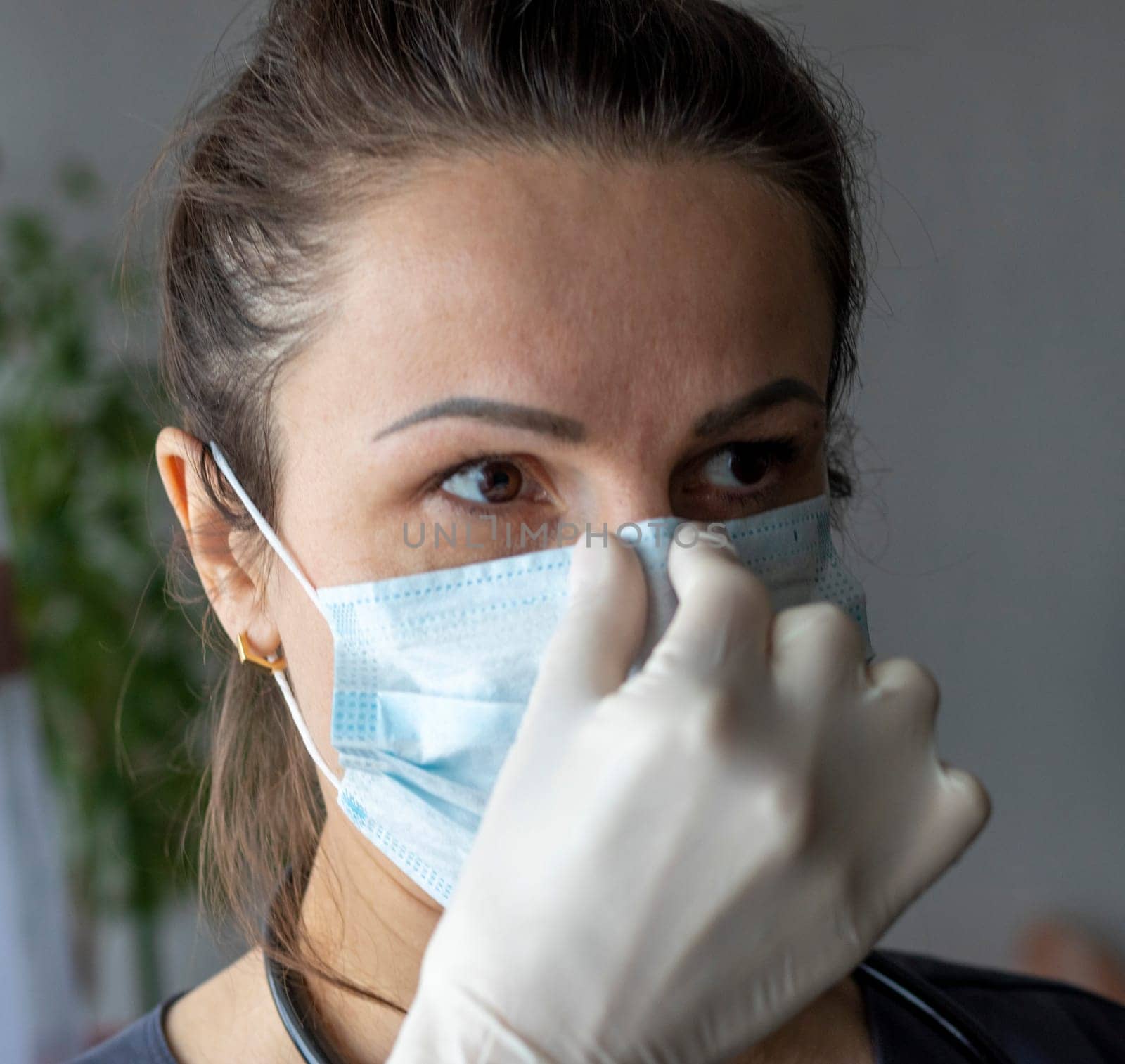 Shot of the nurse in the medical gloves holding medical mask