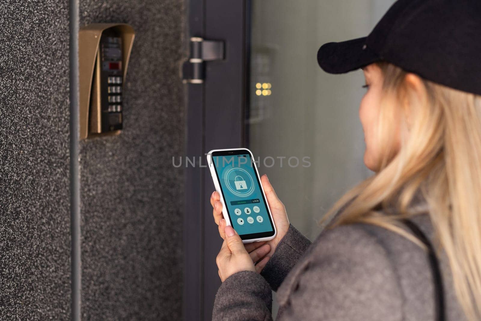 woman uses smartphone to open the door of his house by Andelov13