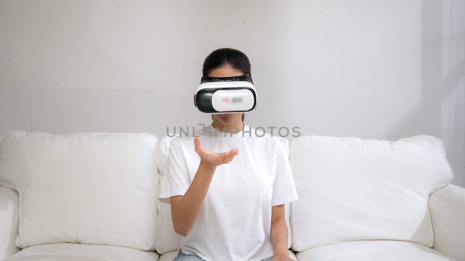 Young woman using virtual reality VR goggle at home for vivancy experience by biancoblue