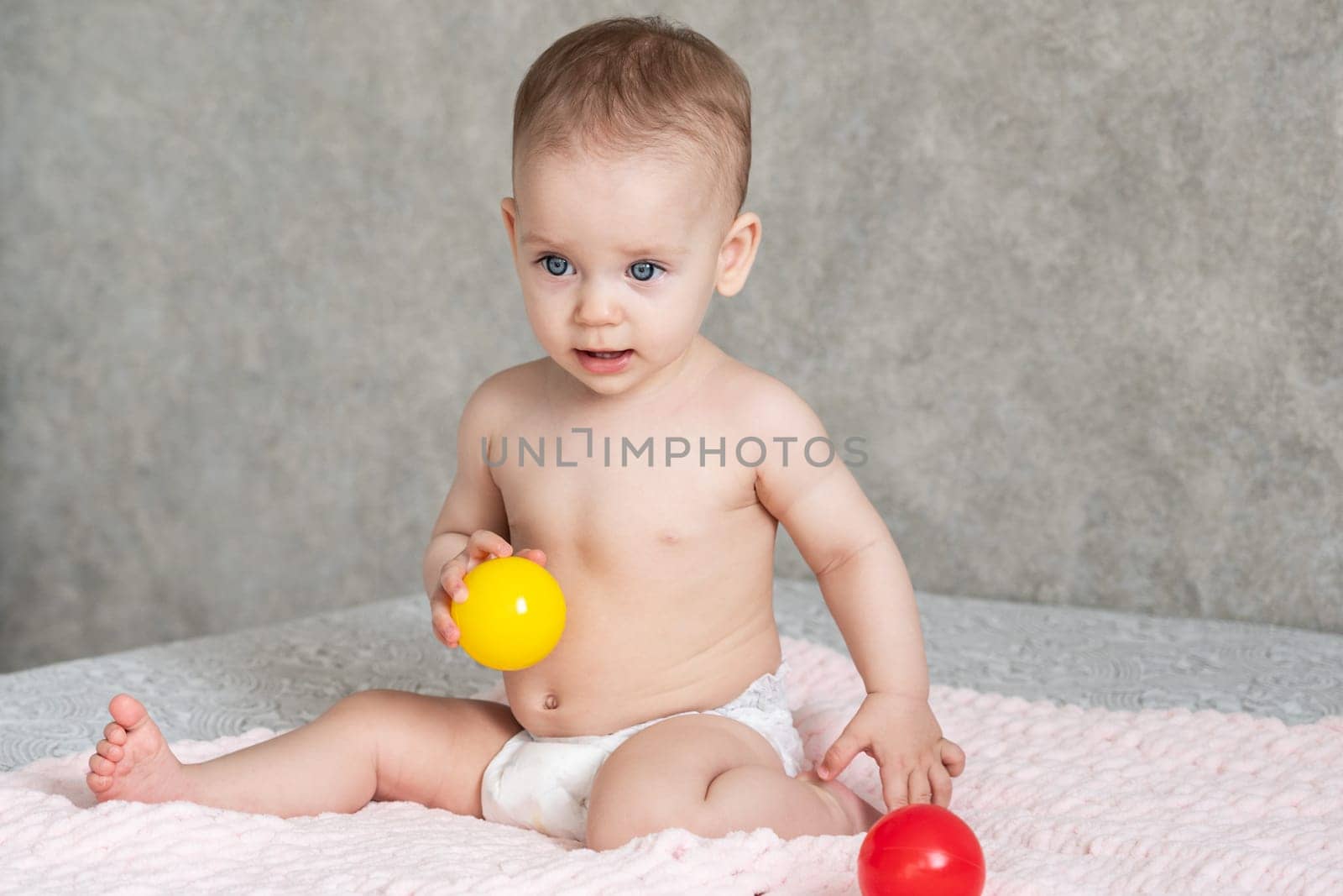 The child froze in delight and throws away the colored balls he is playing with.