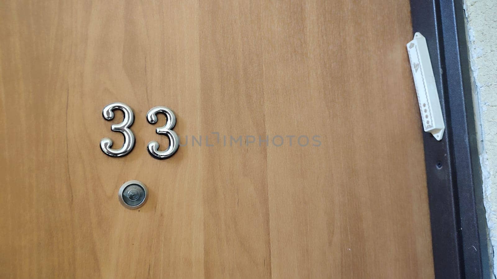 numbers 33 on a white exterior apartment door, symbol objects, sky. High quality photo