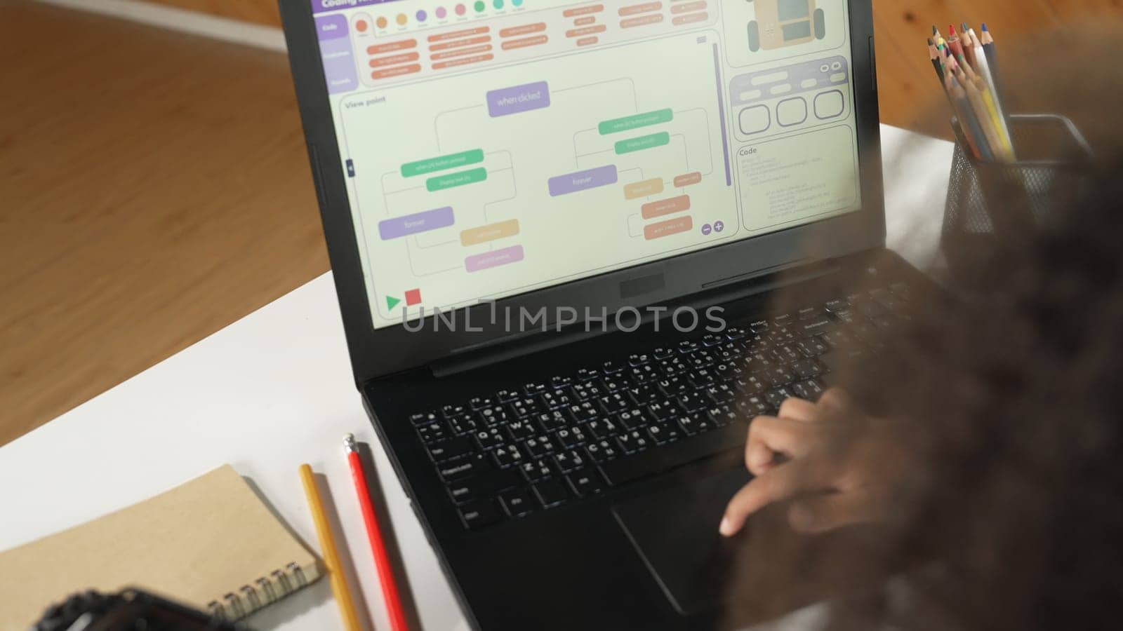 African girl moving touch pad while using laptop programing code and writing prompt code in STEM education. Children learning to designing setting engineering prompt at school. Top view. Erudition.