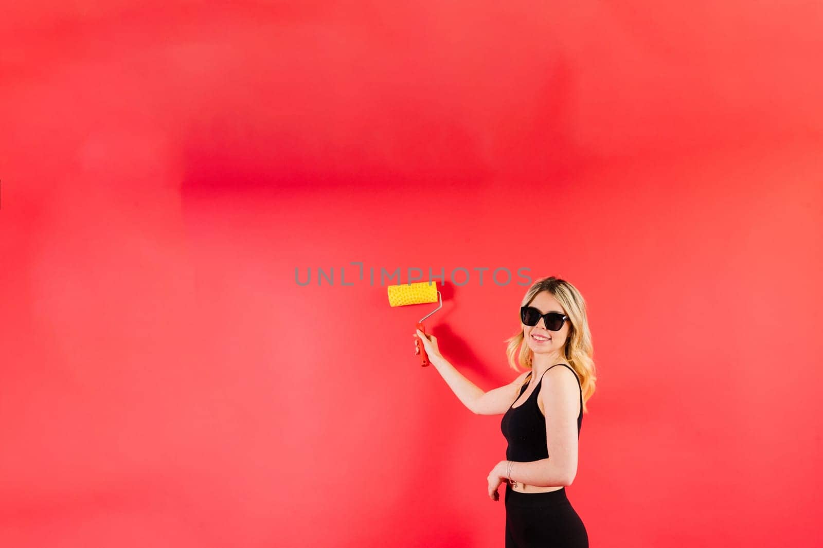 Young woman with roller brush on red white backgrounds Instruments accessories for renovation room