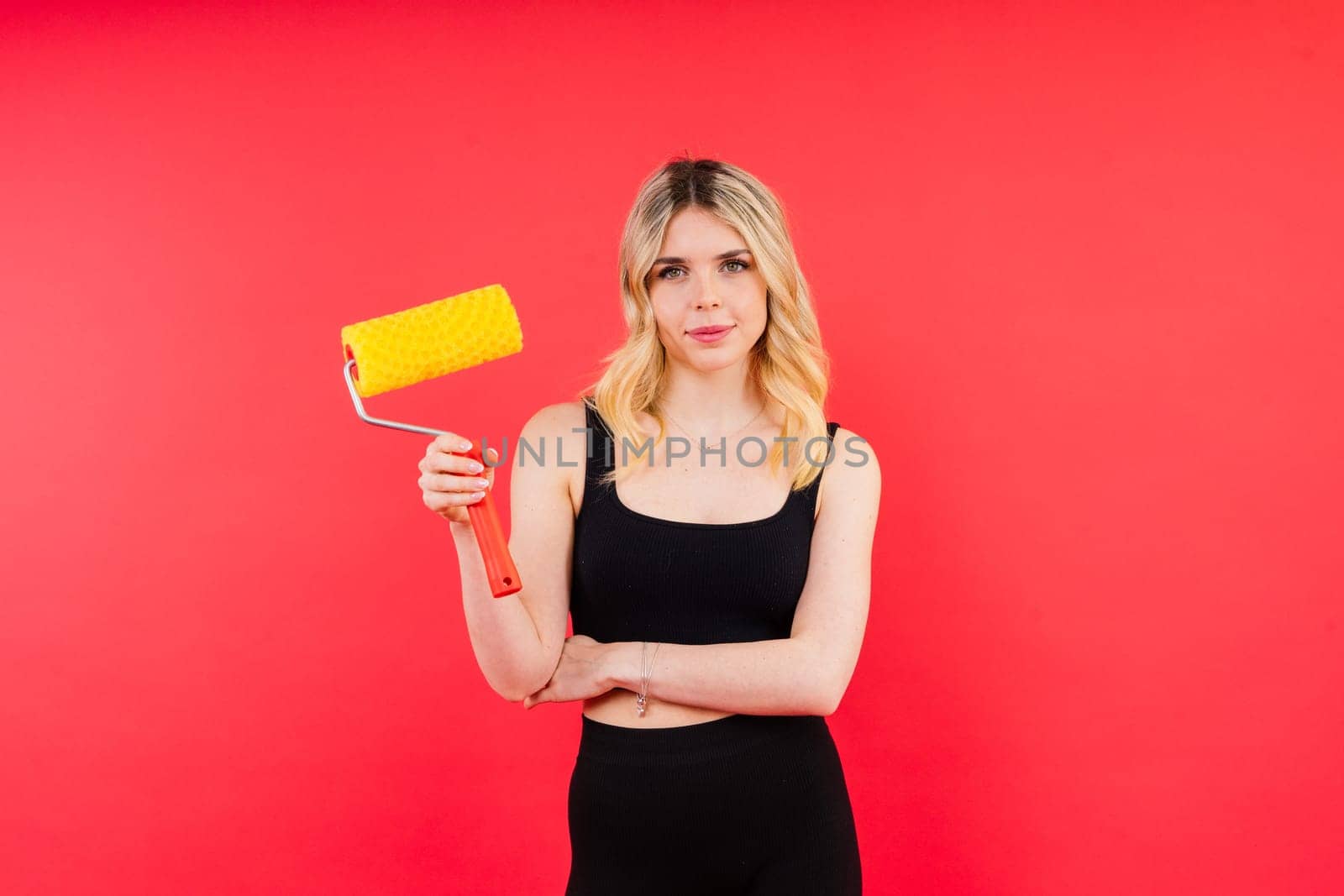 Young woman with roller brush on red white background Instruments accessories for renovation room by Zelenin