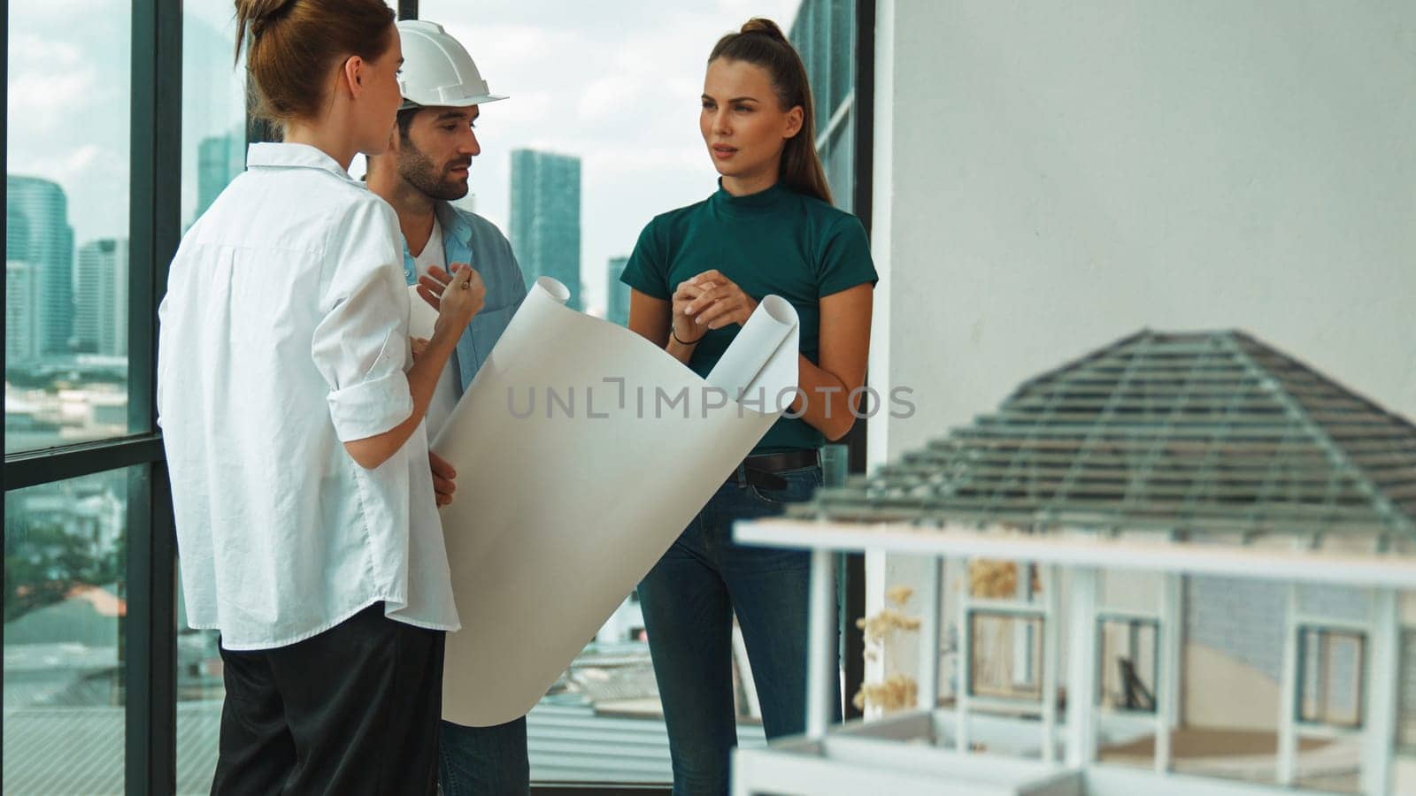 Professional architect engineer team talking, sharing, brainstorming about design while manager hold at project plan. Young architect holding plan while manager listen and point at plan. Tracery