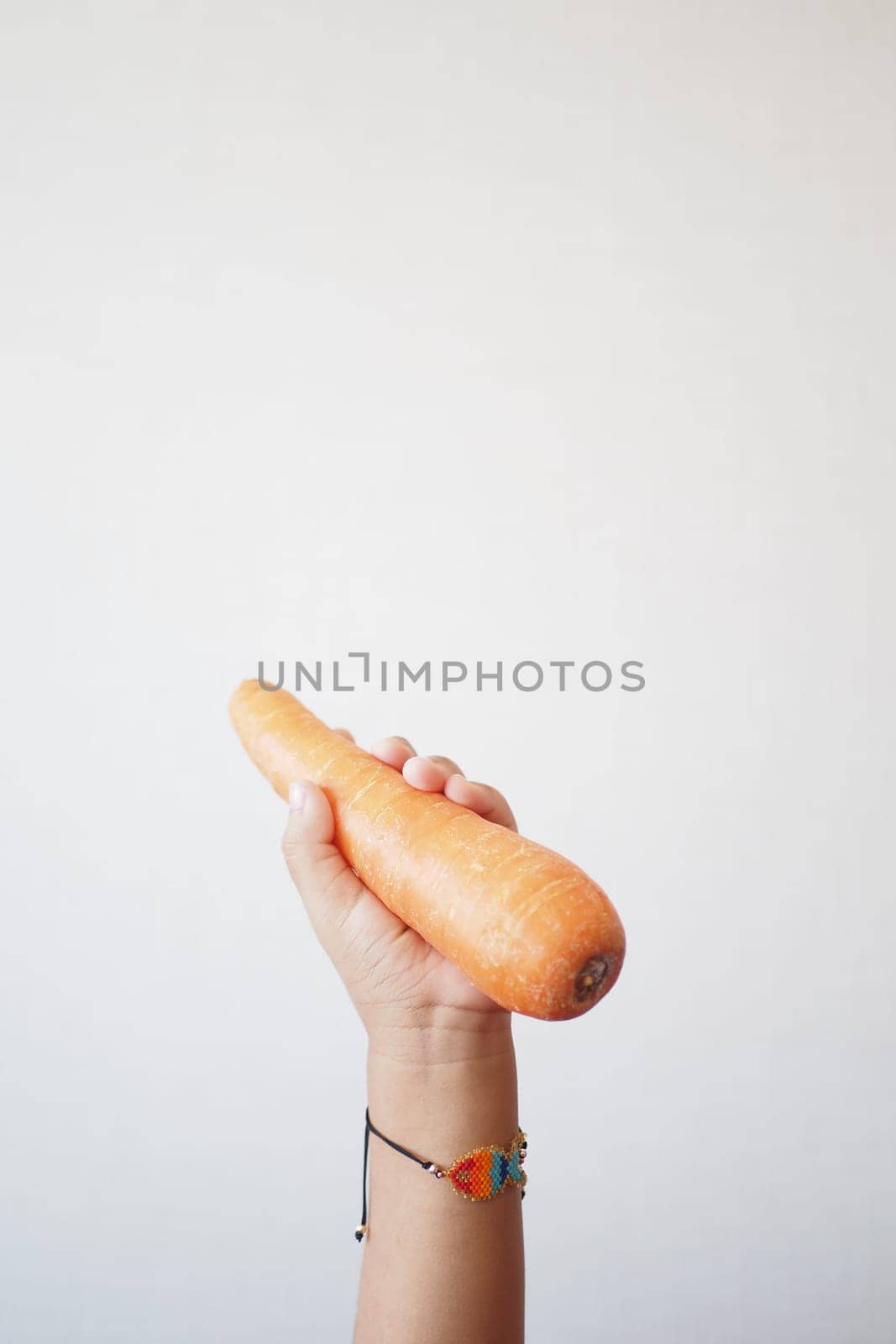 A child is holding a carrot as a food ingredient in their hand by towfiq007