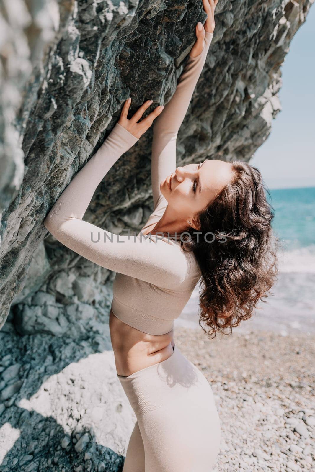 Woman travel sea. Sporty happy middle aged posing on a beach near the sea on background of volcanic rocks, like in Iceland, sharing travel adventure journey by panophotograph