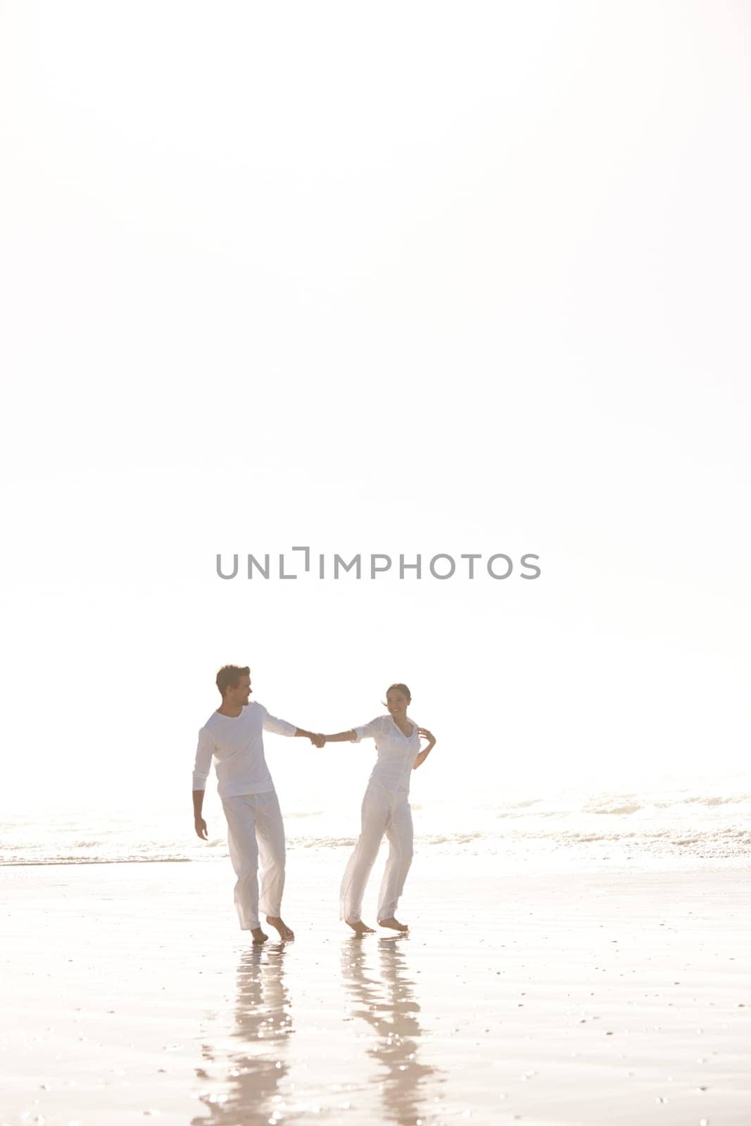 Couple, ocean and holding hands for walk on beach, travel and commitment with trust and bonding outdoor. Love, care and support in relationship, honeymoon or anniversary with fun or playful in nature by YuriArcurs
