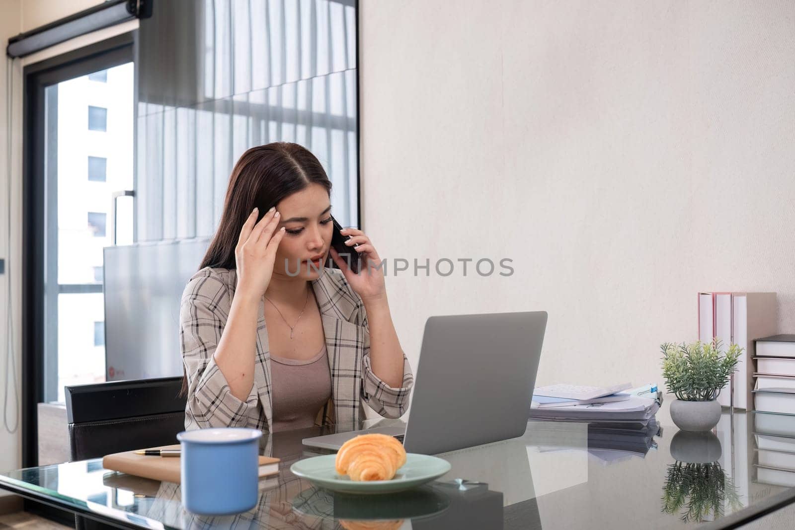 Young woman has stress symptoms from working at home. While talking in an online meeting by wichayada