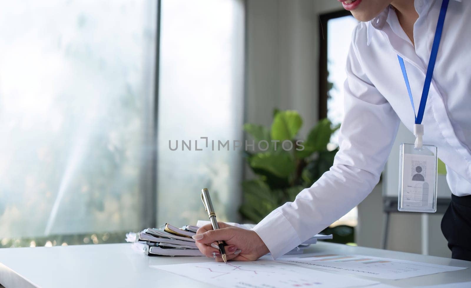A businesswoman with determination takes note, write work plan and graphs the company's financial schedule in her office..